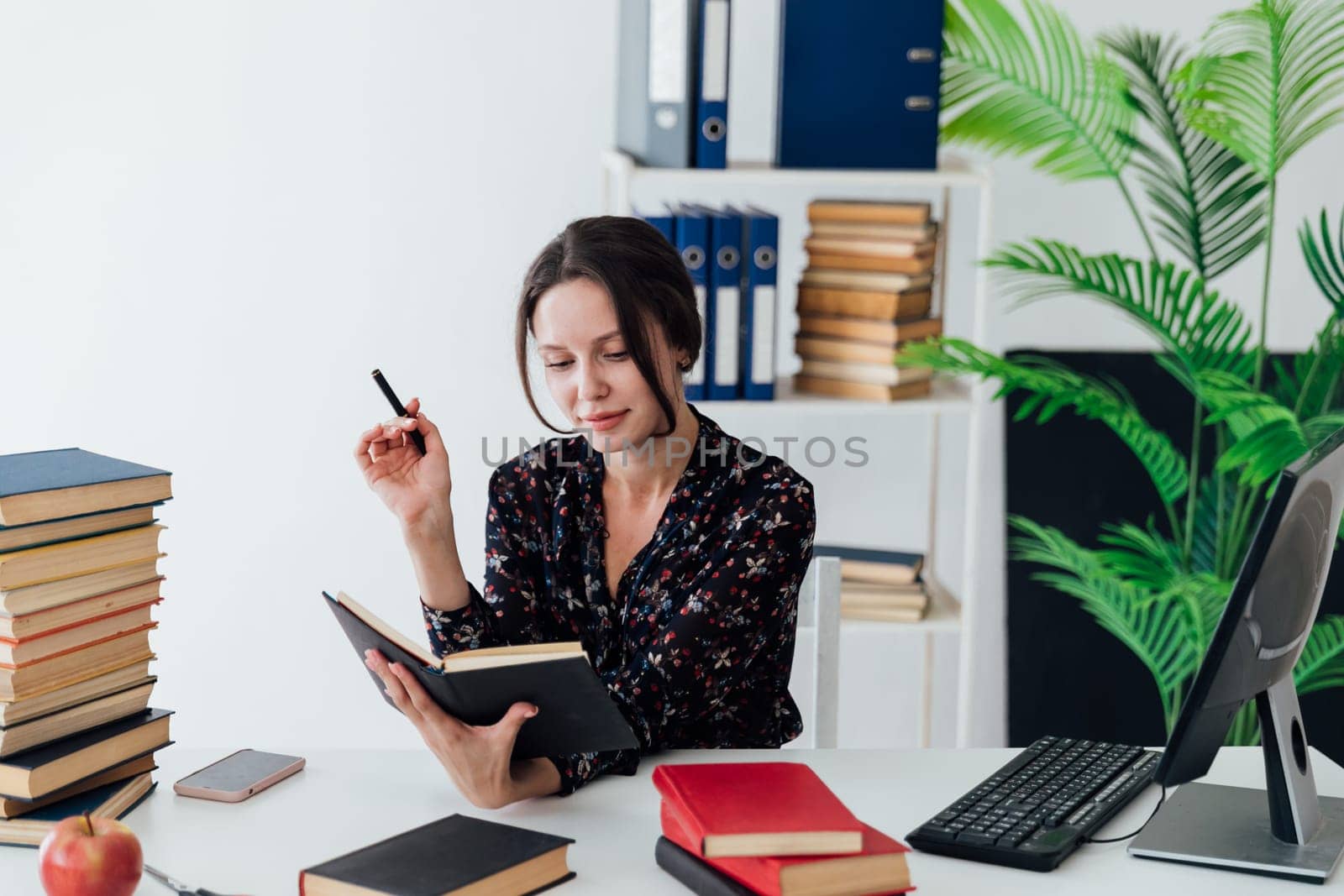 a woman in the office reading a book teacher teaches lessons preparing for classes among many books