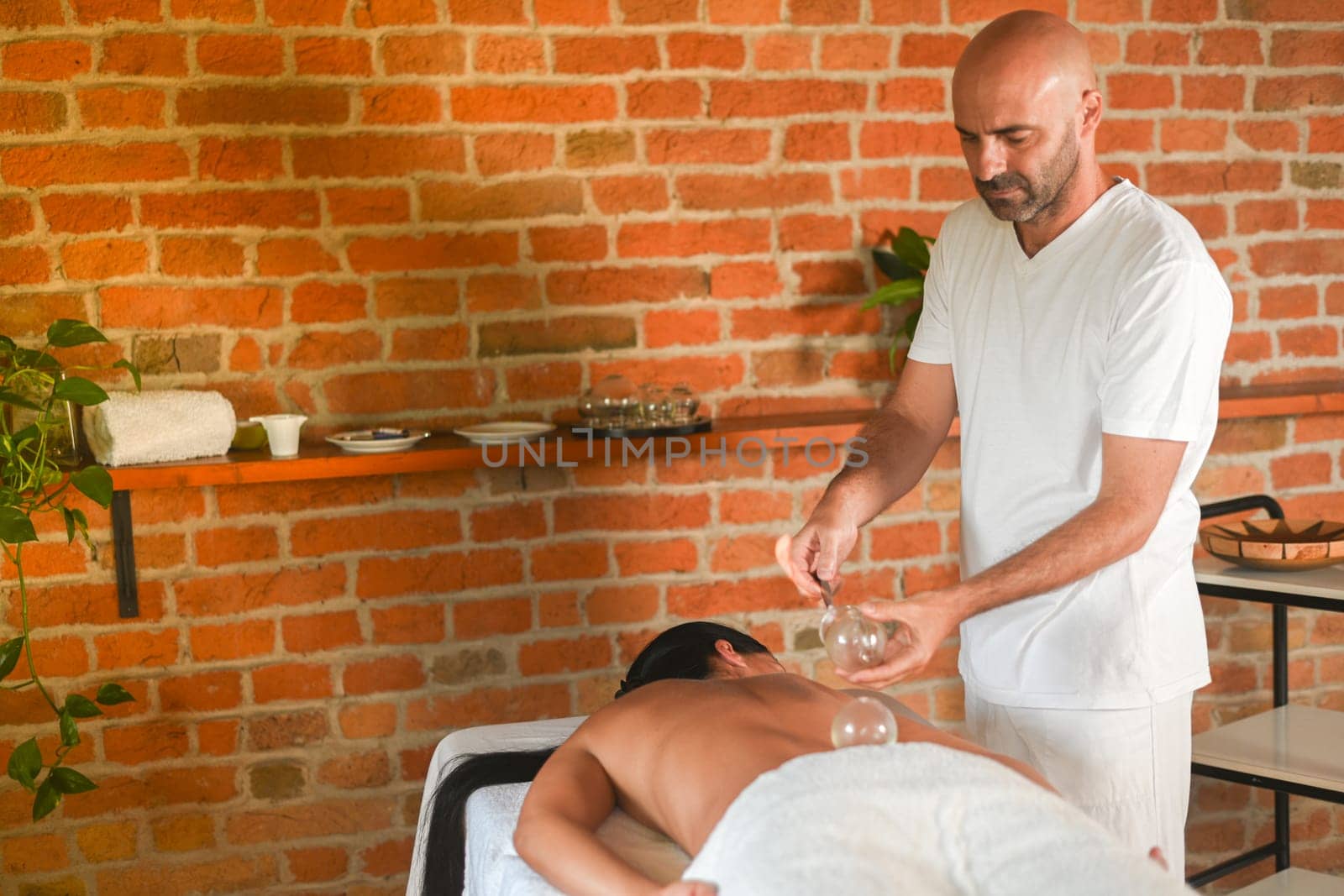 physiotherapist perform cupping therapy with suction massage to hispanic adult fit woman in the therapeutical bed for stress relief