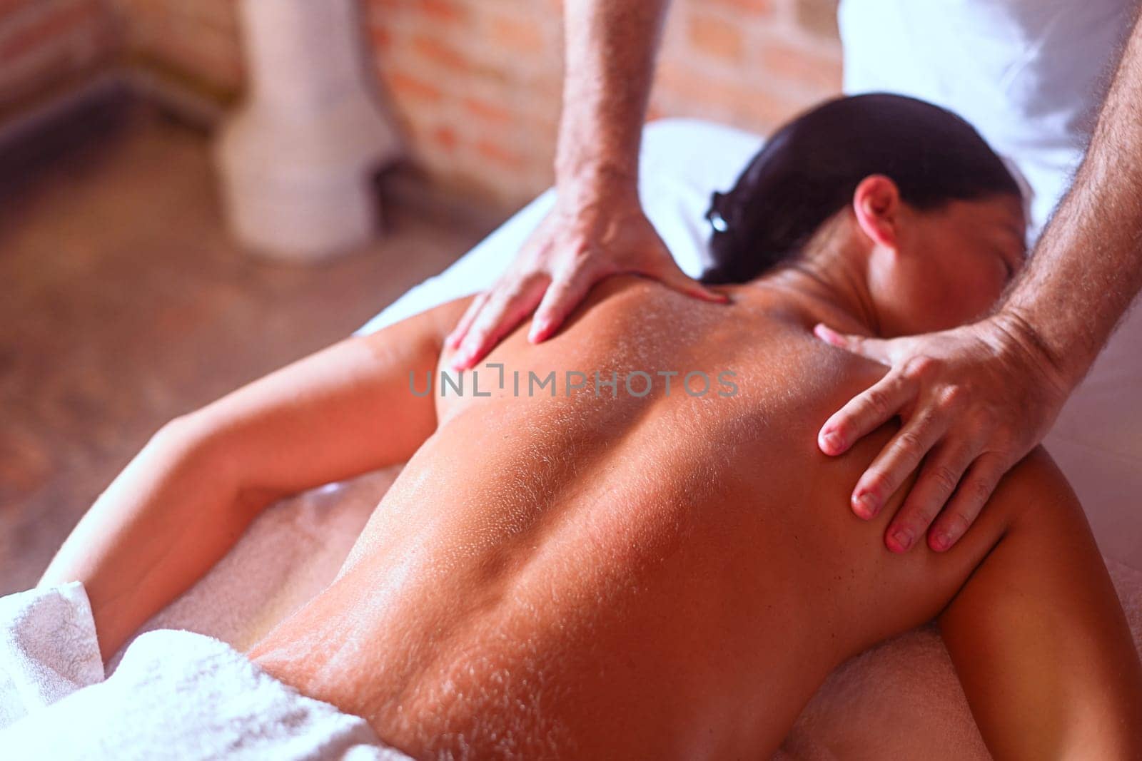 hispanic brunette adult fit woman enjoy massage by physiotherapist in the therapeutical bed at the spa