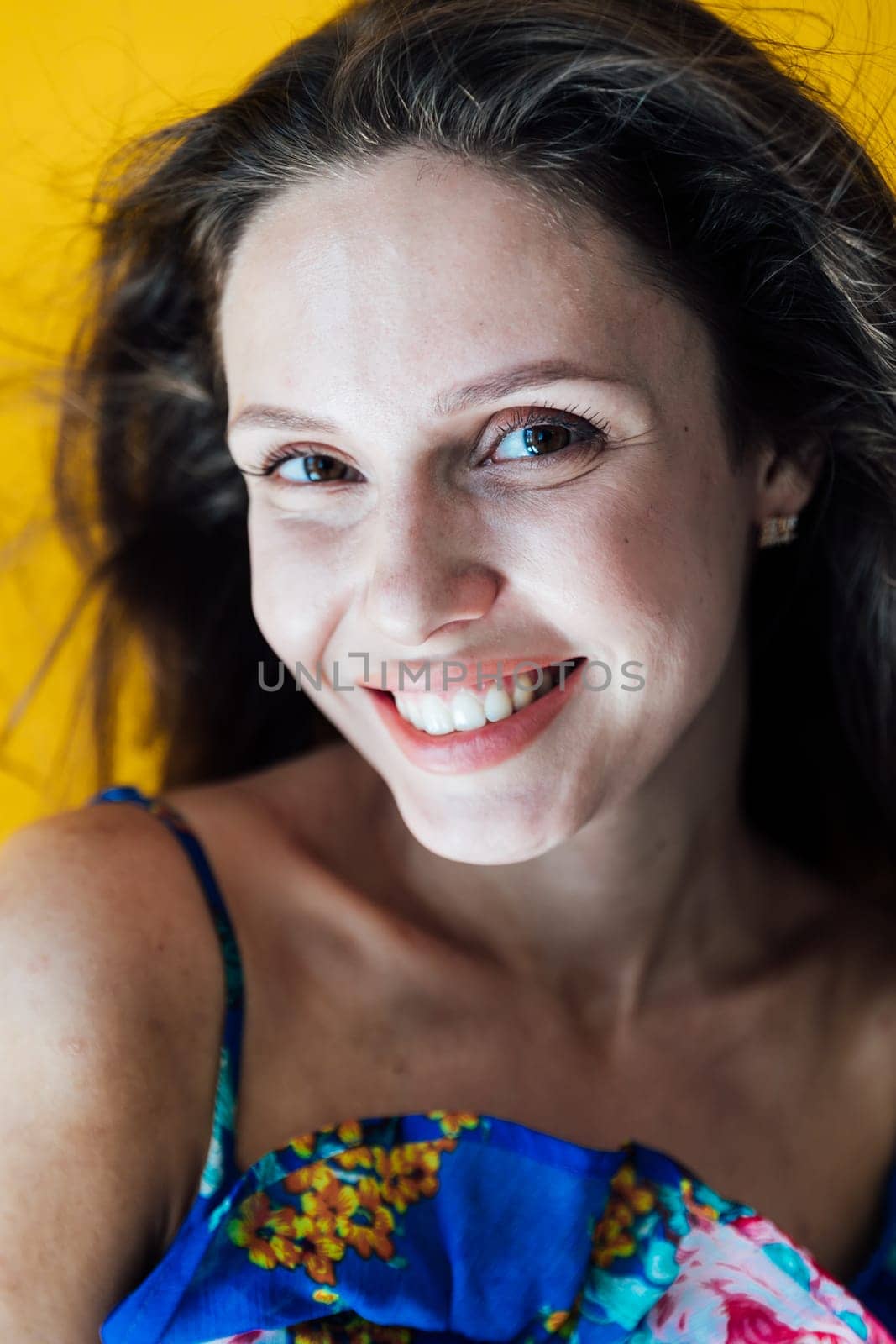 a cheerful woman in a blue floral dress on a yellow background