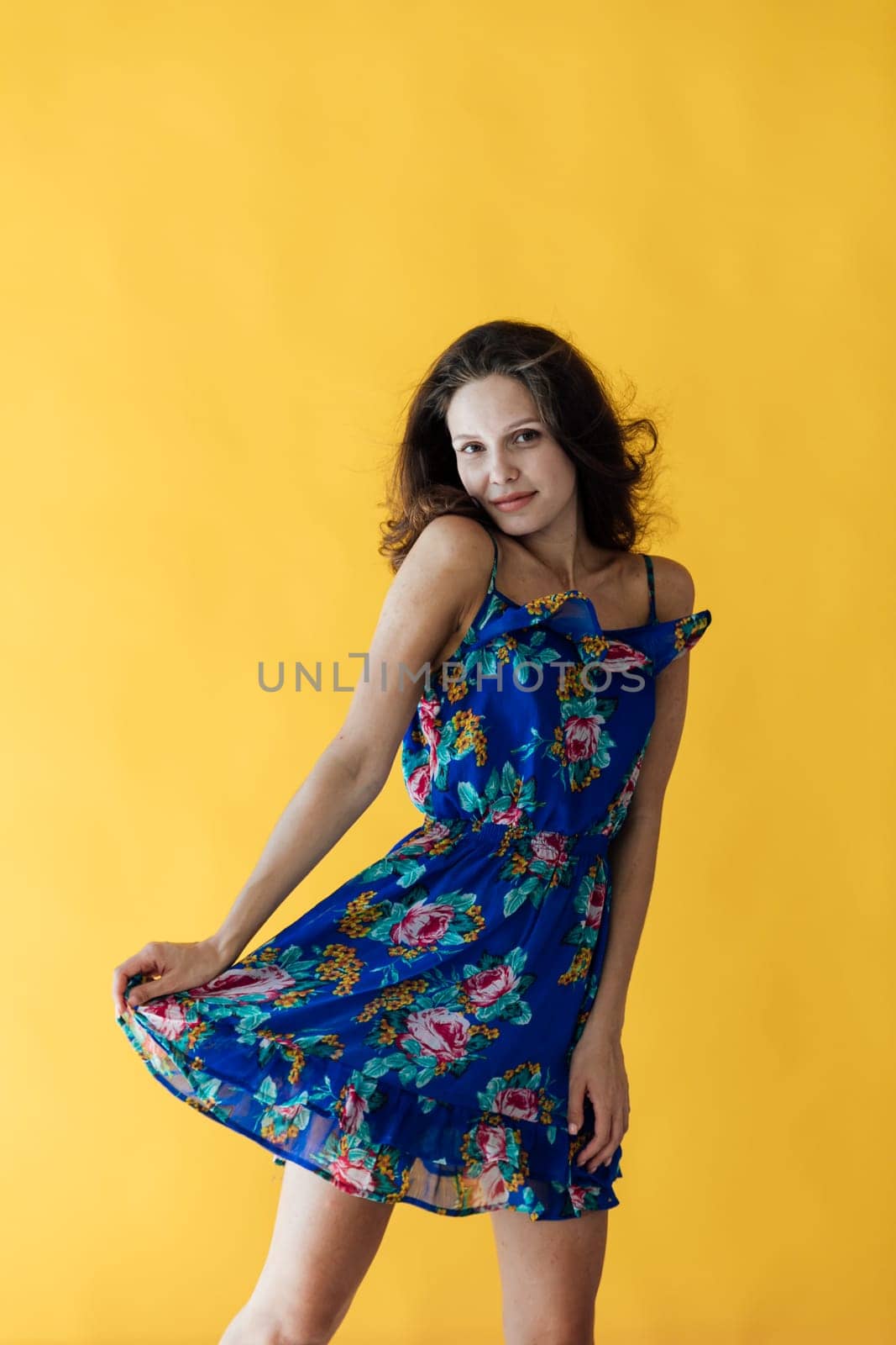 a cheerful woman in a blue floral dress on a yellow background