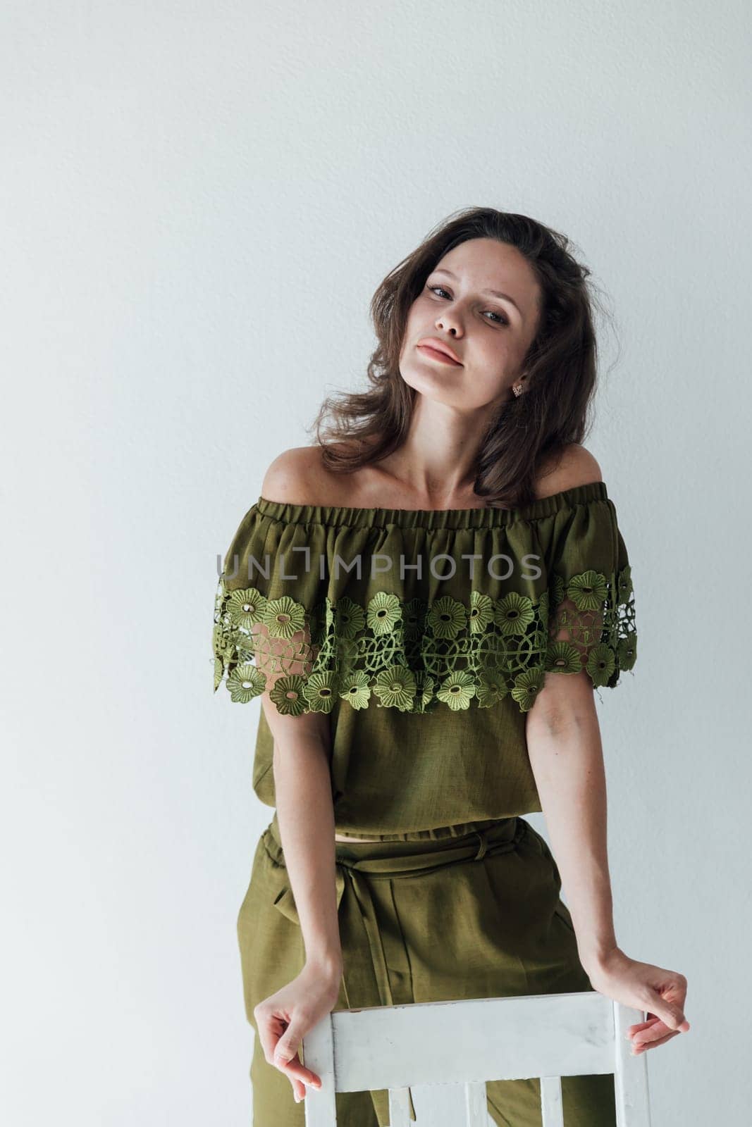 brunette woman in green clothes leaned on a chair