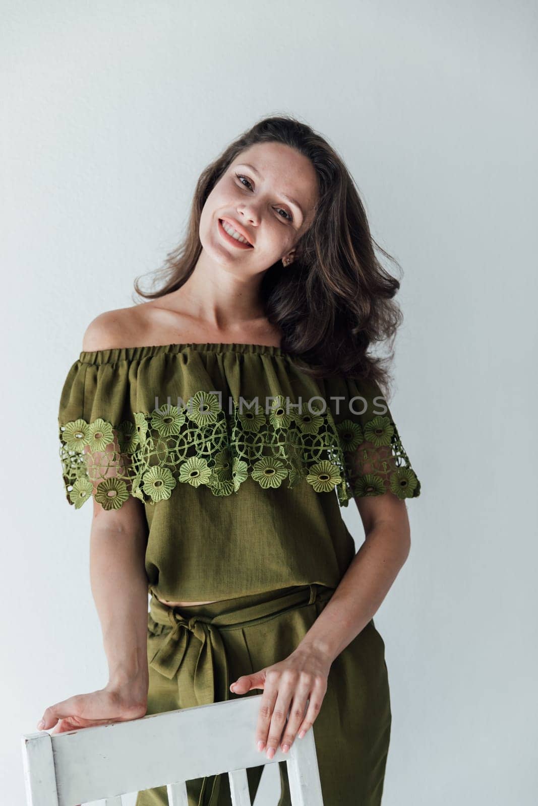 brunette woman in green clothes leaned on a chair