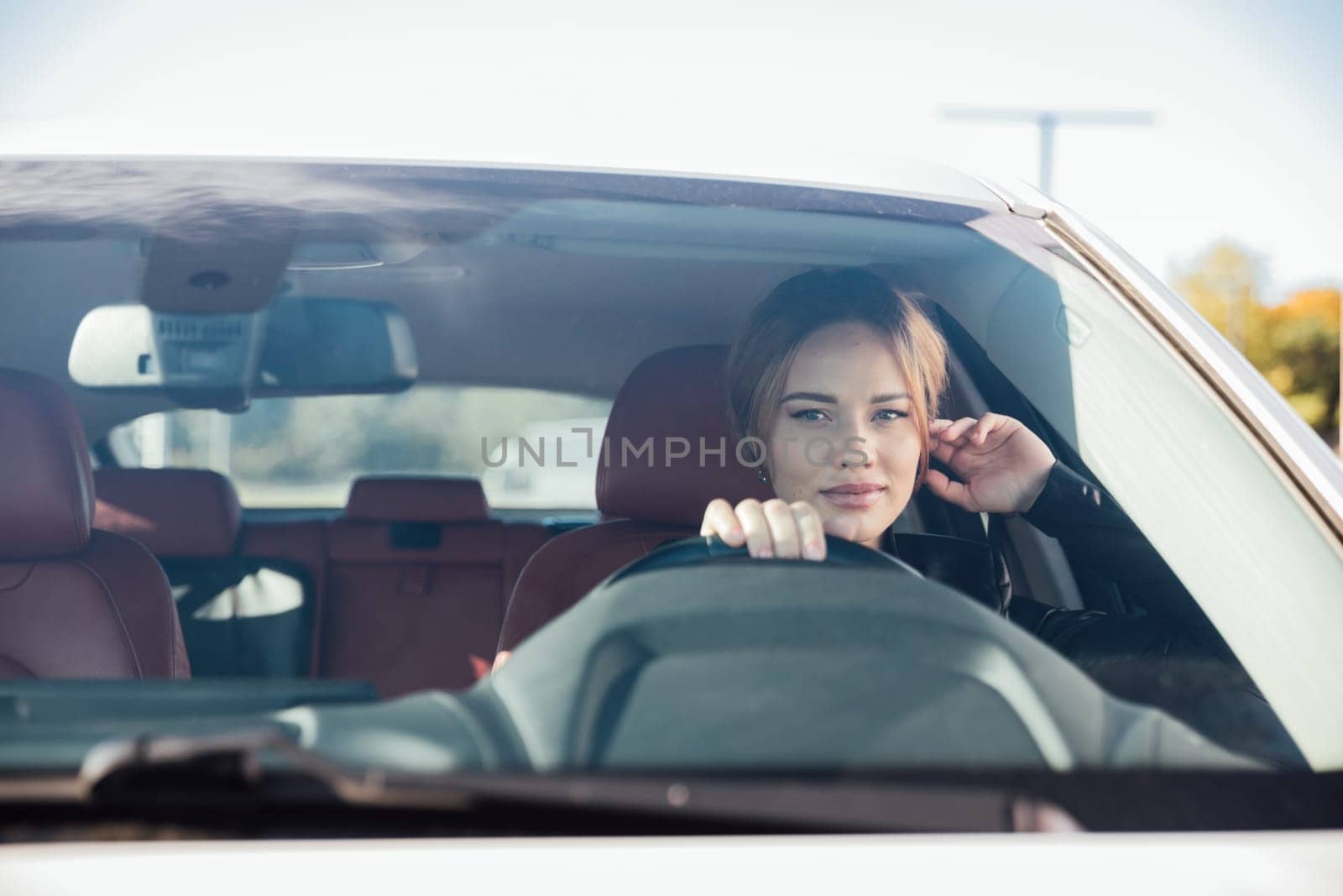 a beautiful fashionable woman sitting behind the wheel of a car