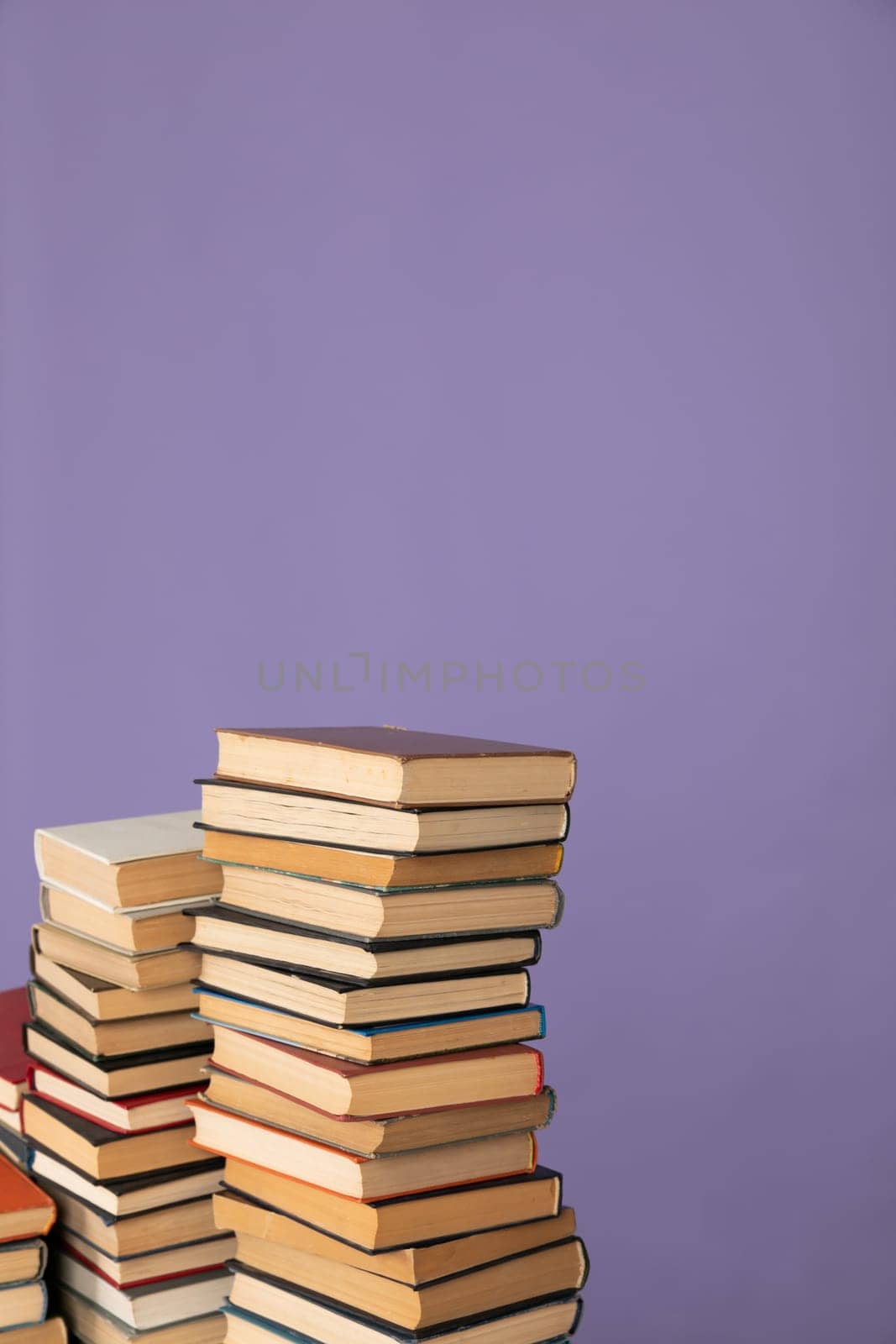 stack of books library for reading and education on a purple background by Simakov