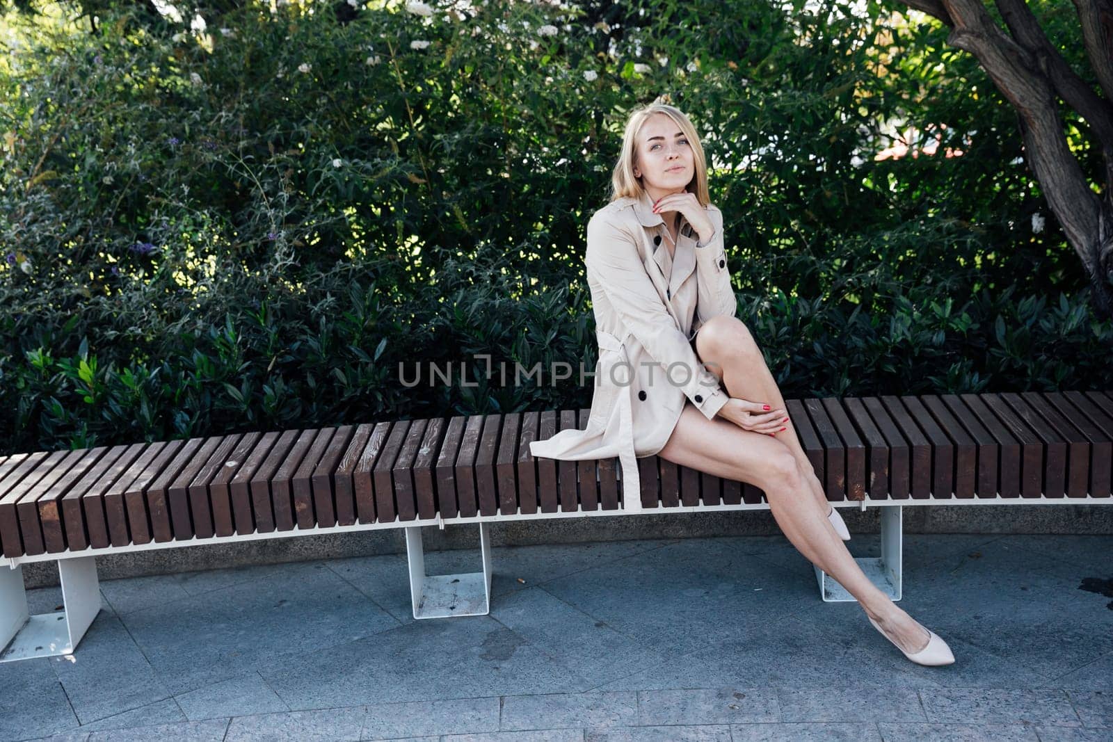 woman in the park sits on a bench near green plants