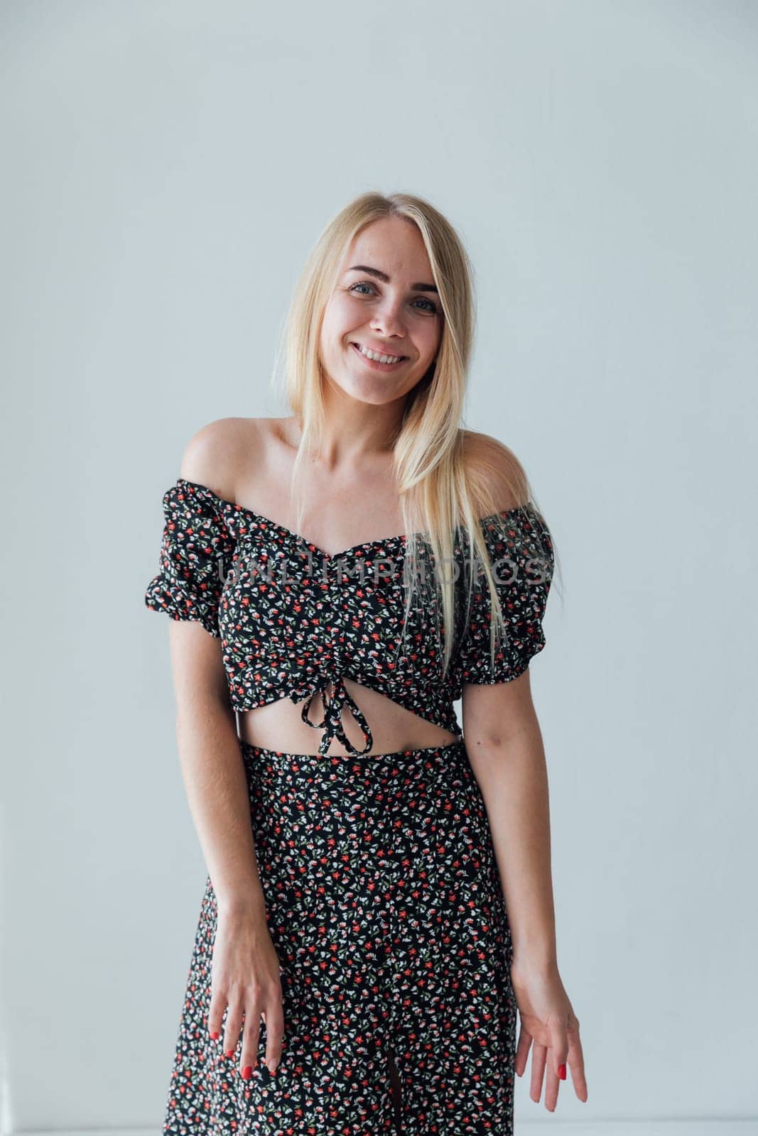 a beautiful blonde in colored clothes poses on a white background