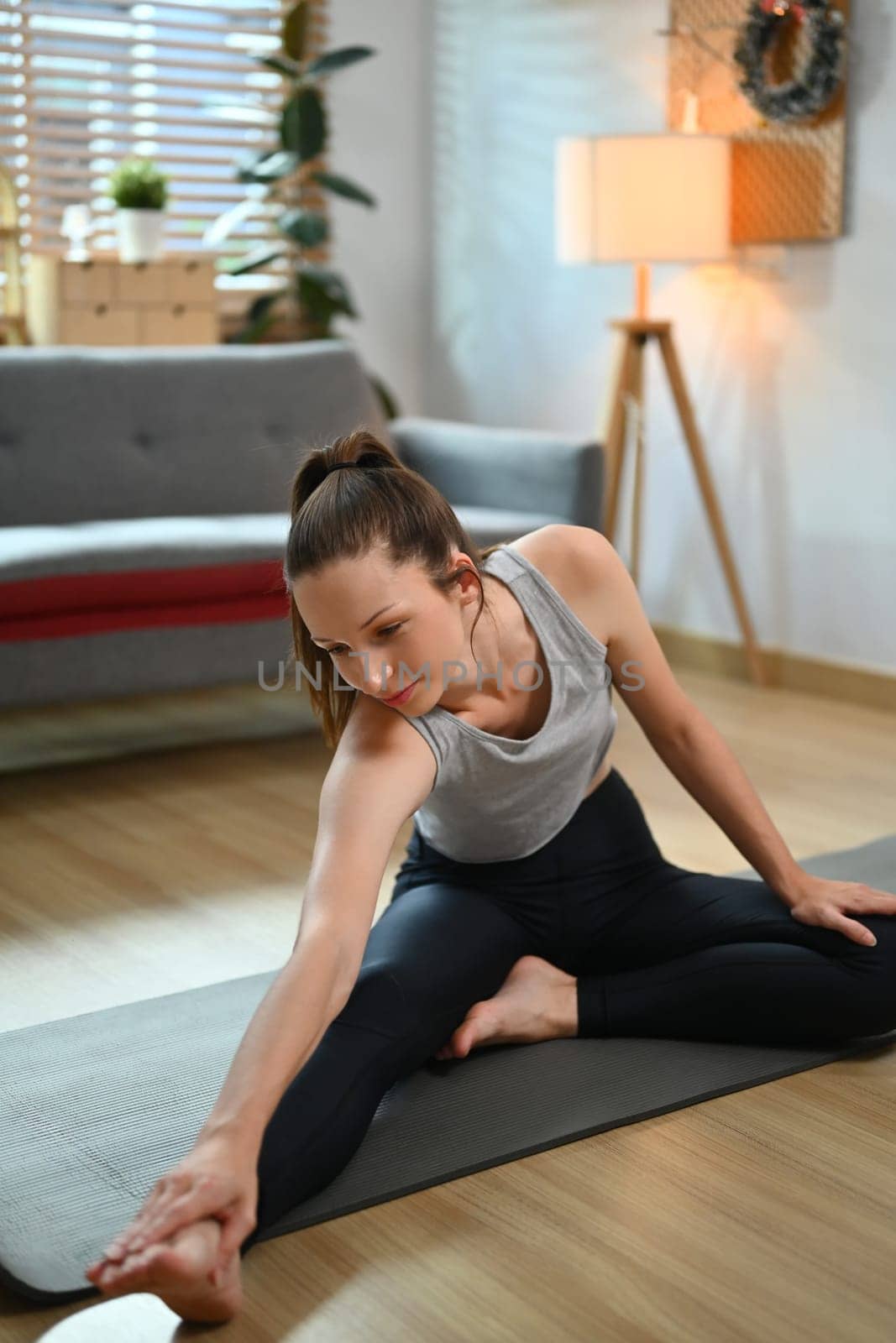Beautiful woman in sportswear doing stretching on yoga mat at home. Healthy lifestyle concept.