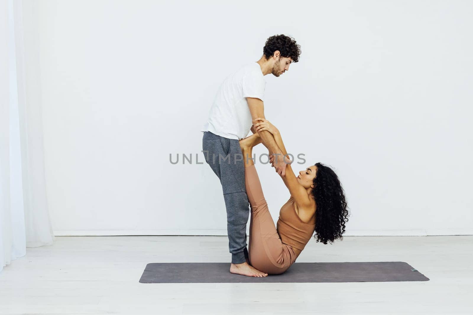 man stretches a woman's arms in yoga training acrobatics