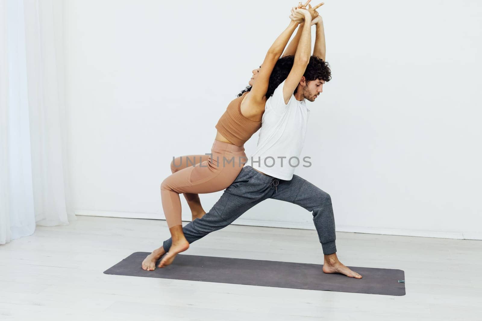 coach stretches a woman's back with yoga in the gym by Simakov