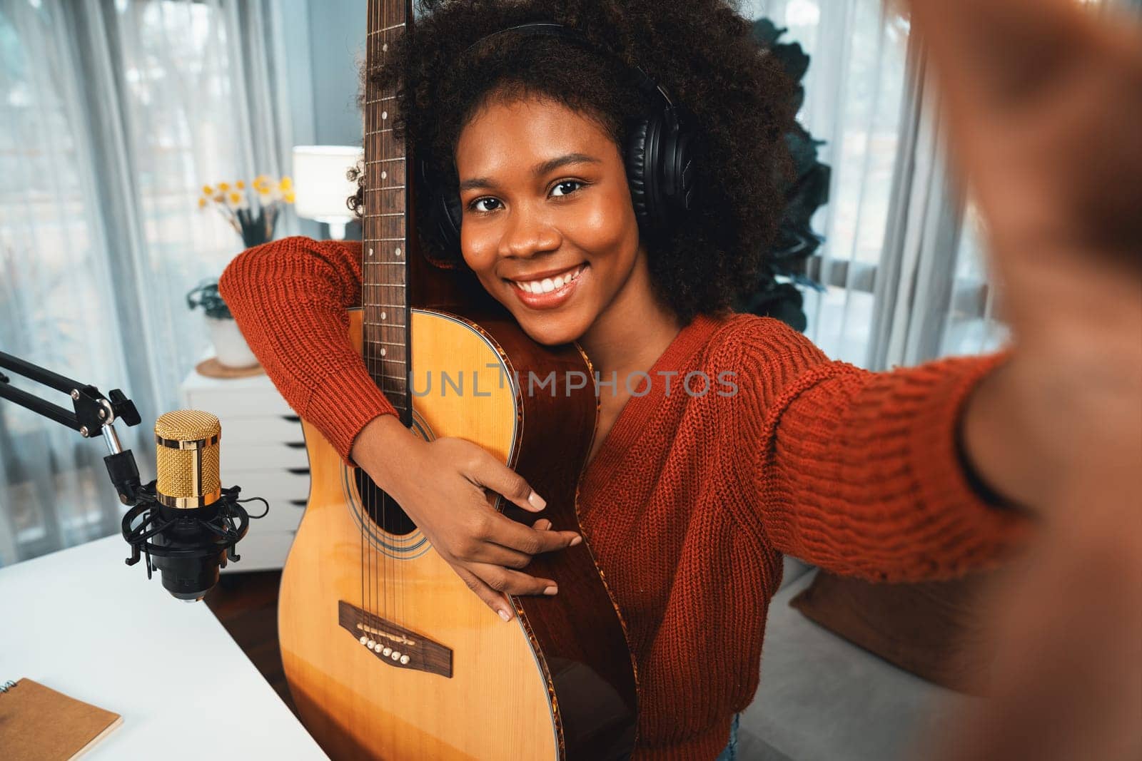 Host channel in musician of young African American with selfie for fans, broadcasting on smartphone in private studio. Decoration of equipment of headsets and recording microphone. Tastemaker.