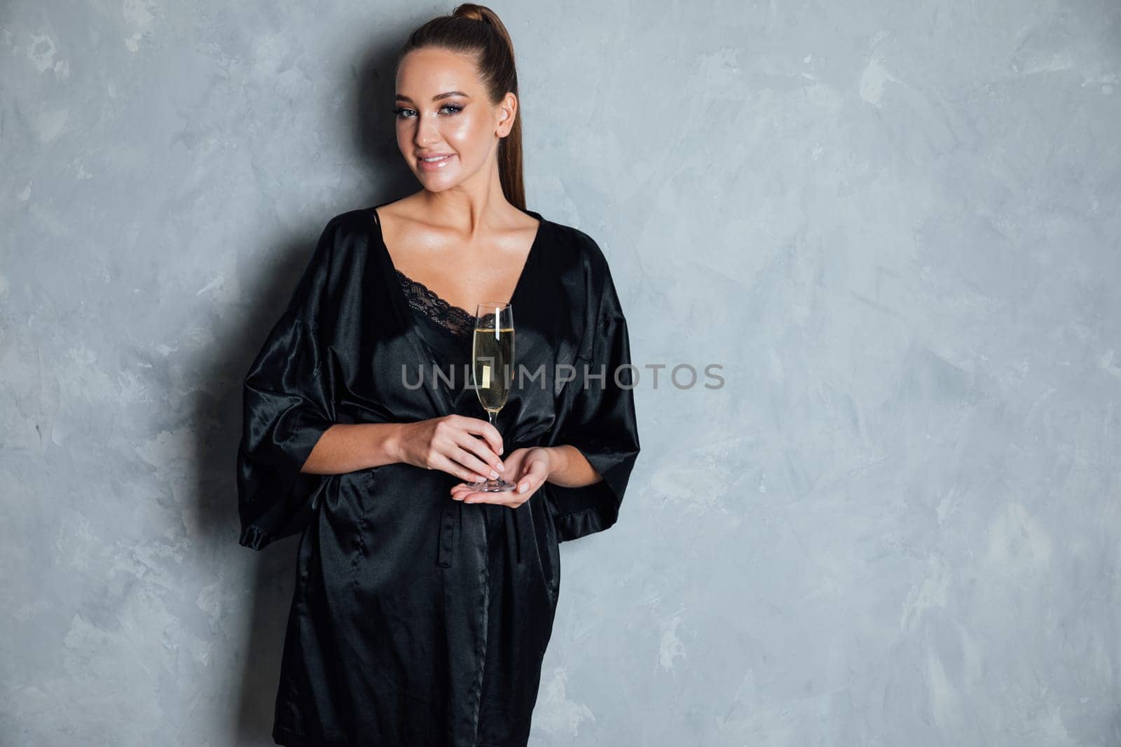 a woman in black nightwear holds a glass of champagne in her hands