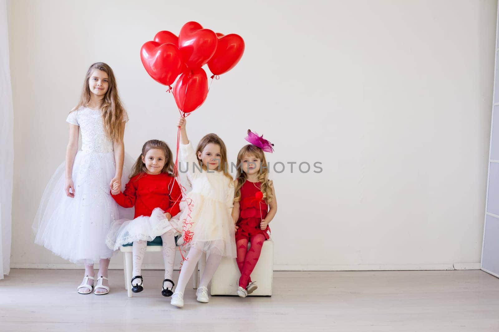 a beautiful children with red balls sitting on chairs