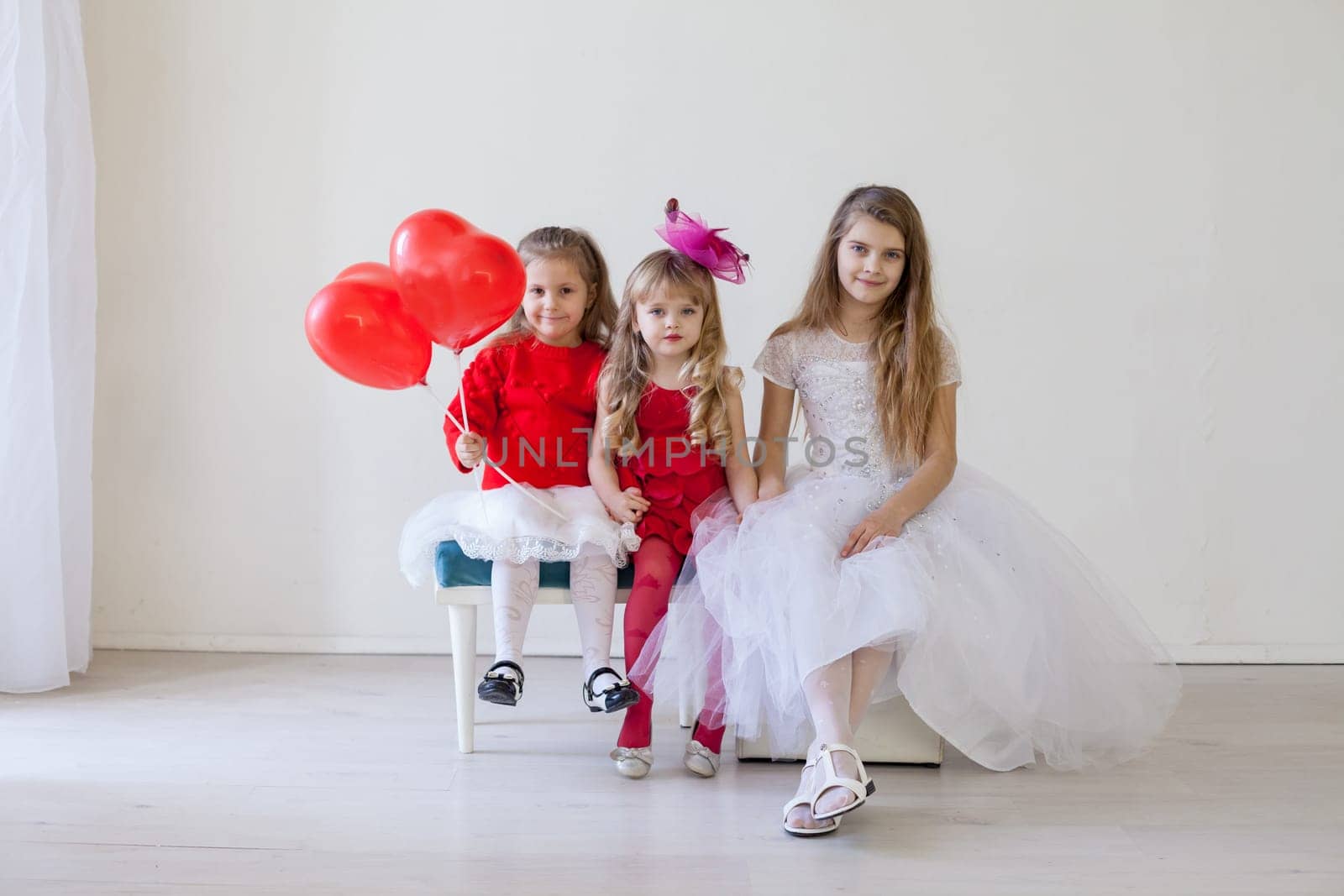 beautiful children with red balls sitting on chairs by Simakov