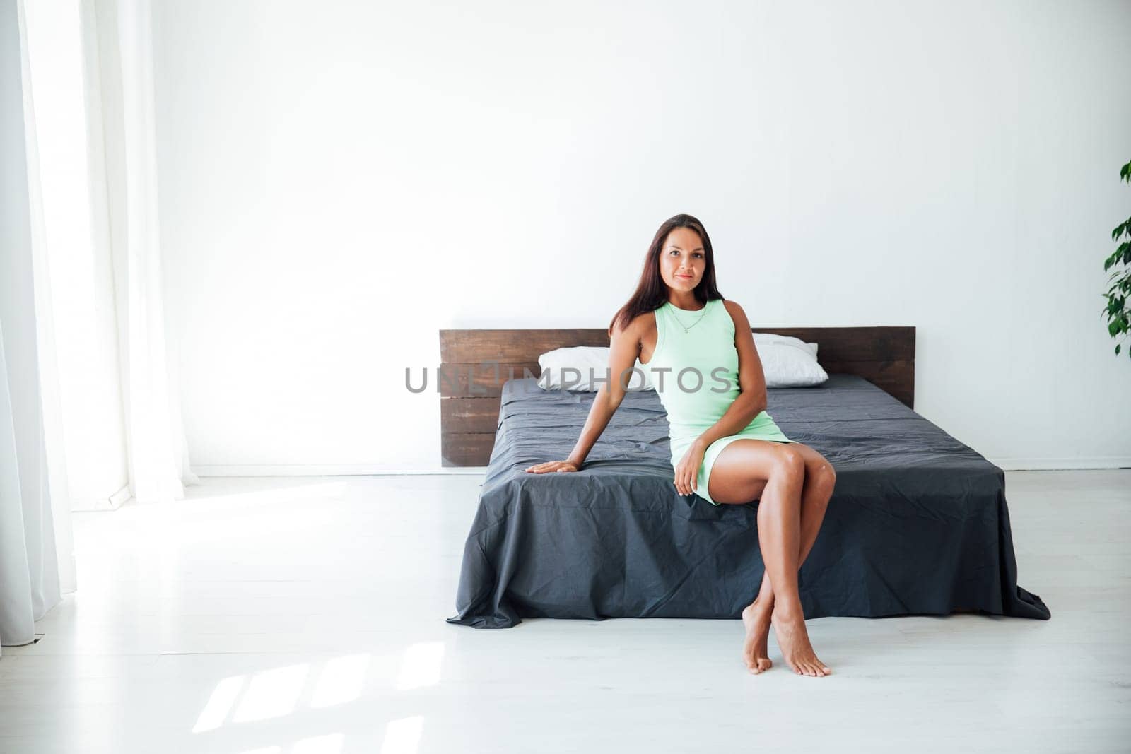 brunette woman sitting in a room on a bed in a hall with a pallet