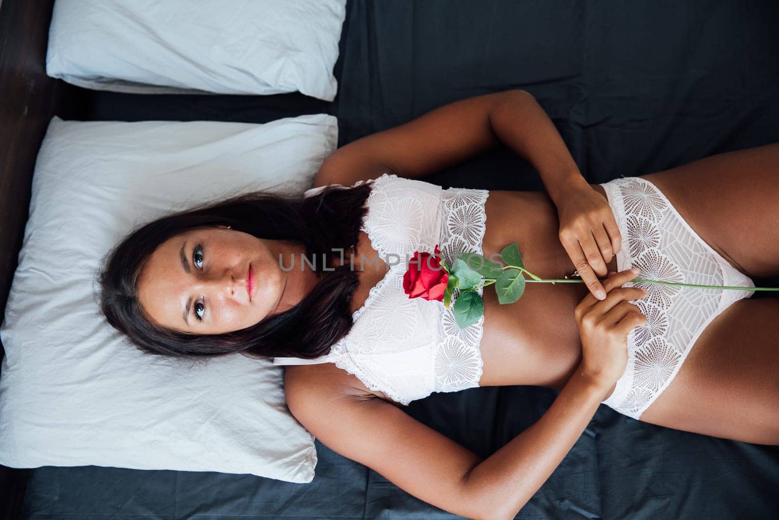 woman lies on a bed with a red rose in a bedroom room