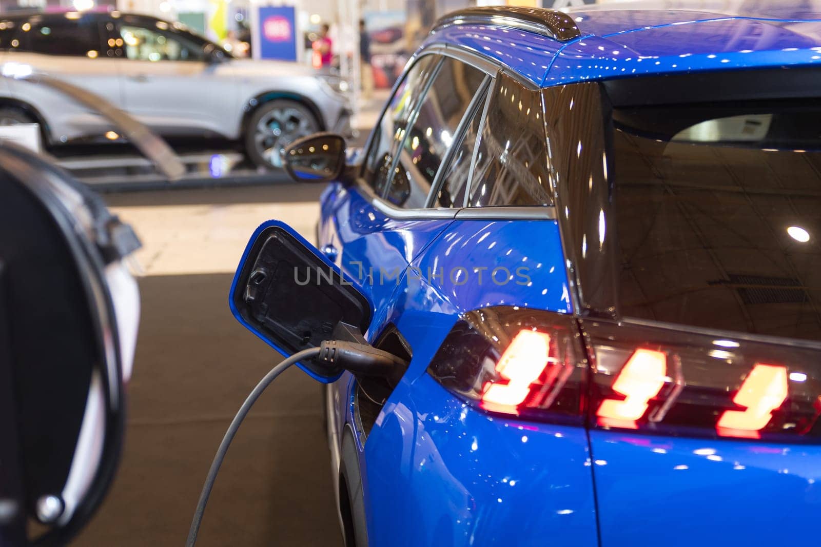 A blue car plugged in to an electric charger