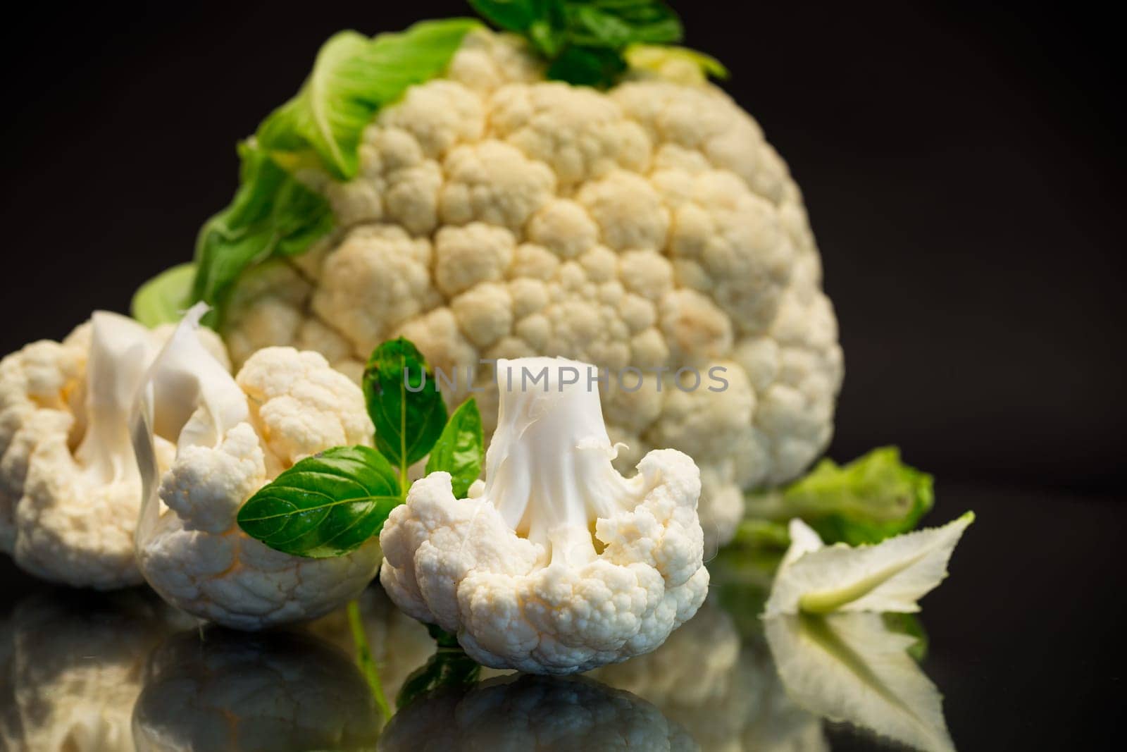 slices of raw small raw cauliflower isolated on black background