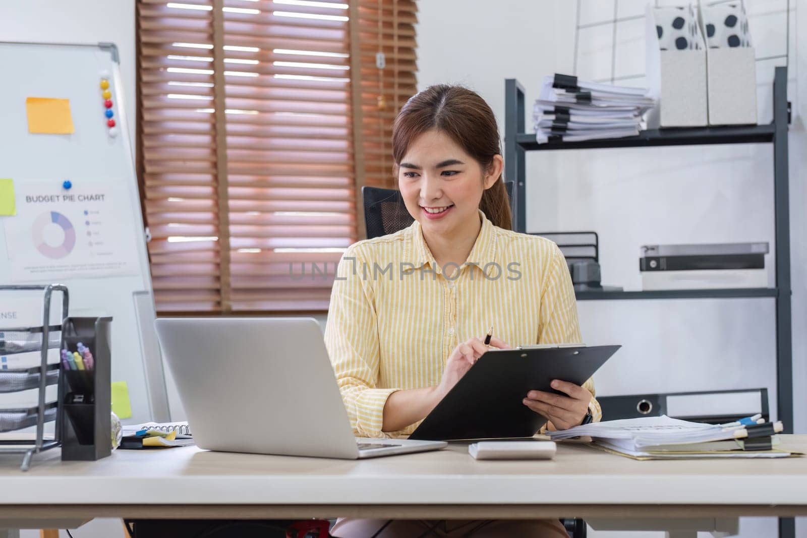 Businesswoman uses laptop to do finance, mathematics on wooden table in office and business background, tax, accounting, statistics and analytical research concept..