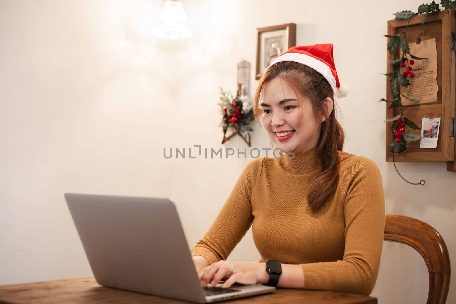 A startup employee writes a report on a laptop on Christmas Eve. In an office decorated with colorful bulbs and lights during the Christmas holidays.