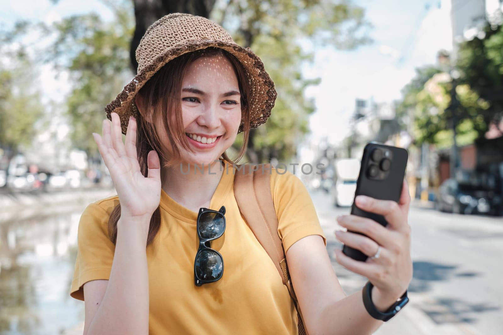 Young Asian tourist walking along city streets and holds a mobile phone on the payment.