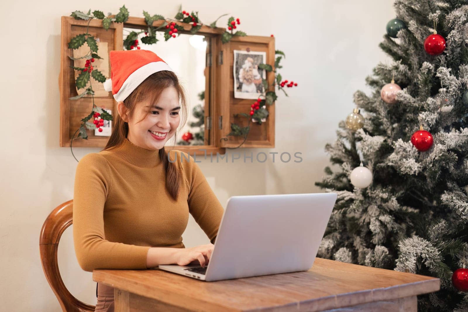 A startup employee writes a report on a laptop on Christmas Eve. In an office decorated with colorful bulbs and lights during the Christmas holidays by wichayada