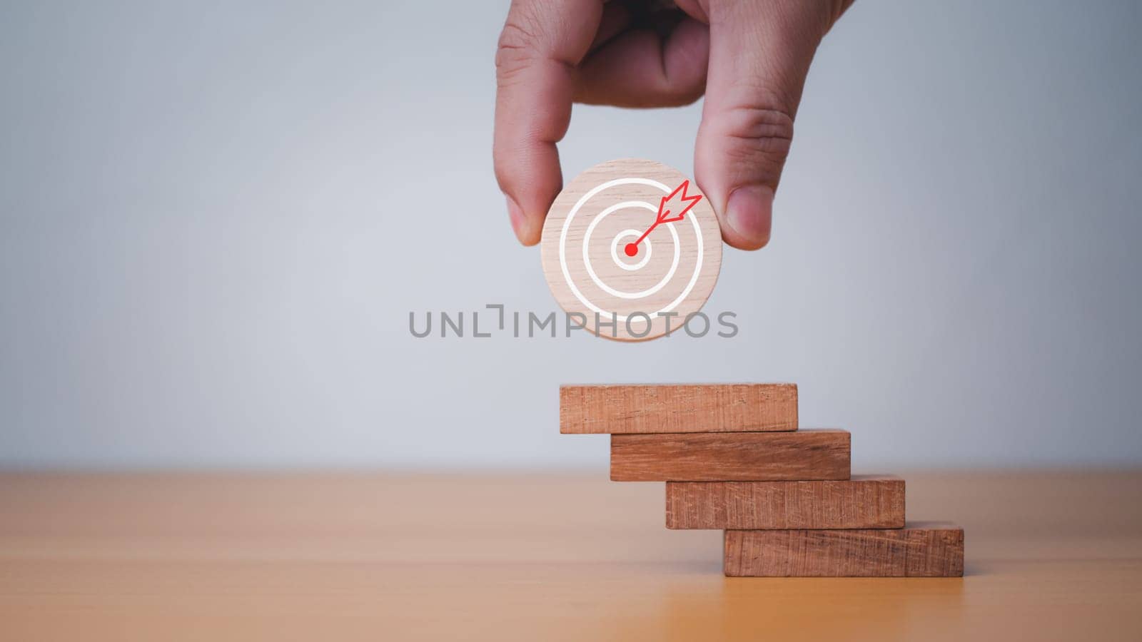 Businessman's hands hold a circular wooden board with a dartboard. It represents the concept of business strategy and target action plan. by Unimages2527