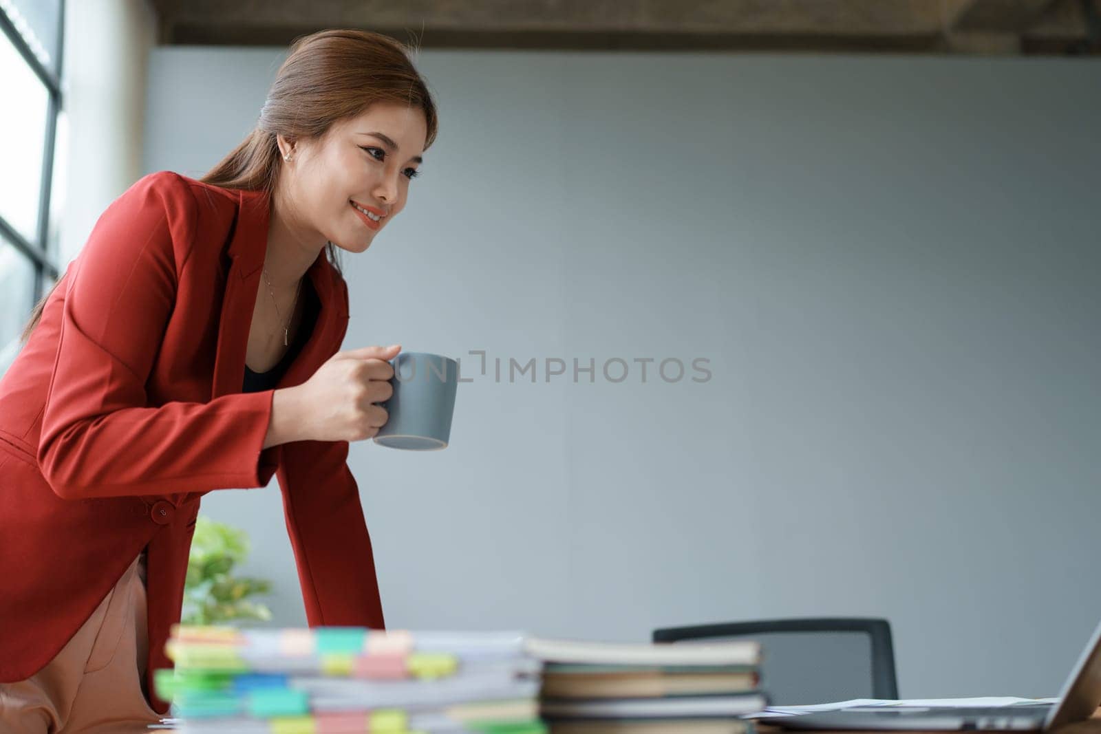 Businesswoman enjoys relaxing with a cup of coffee after a long day. by Manastrong