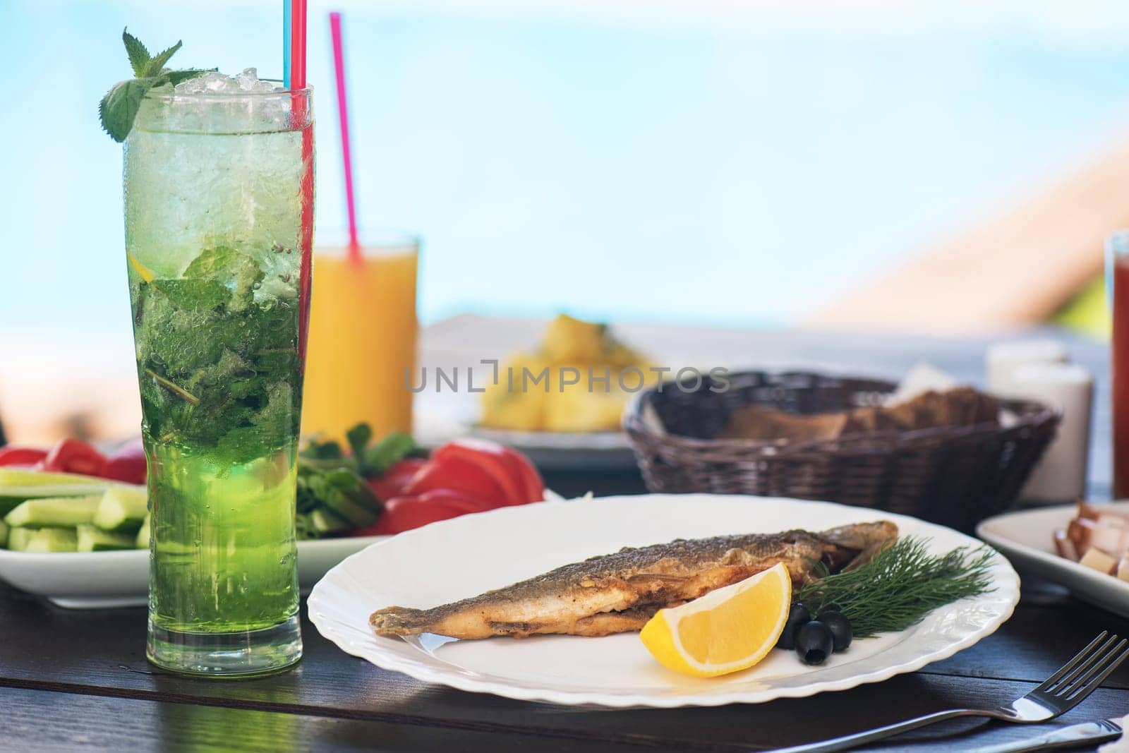 Fried grayling fish on a palte with greens and lemon
