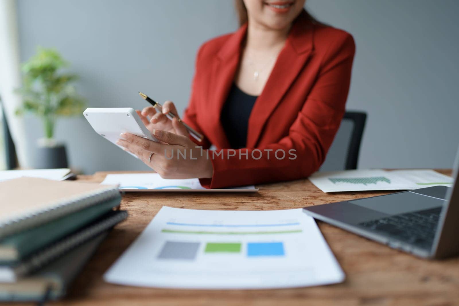 Businesswoman reviewing annual documents and using calculator to calculate budget and profit