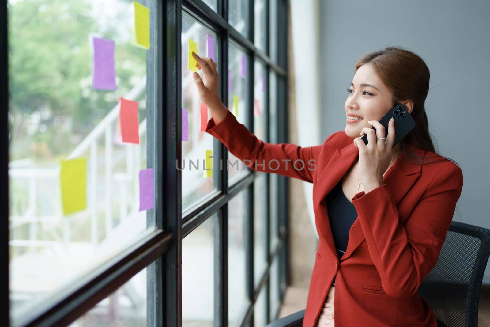 The businesswoman using smartphone mobile discuss the project, and use note paper to jot down important points. by Manastrong