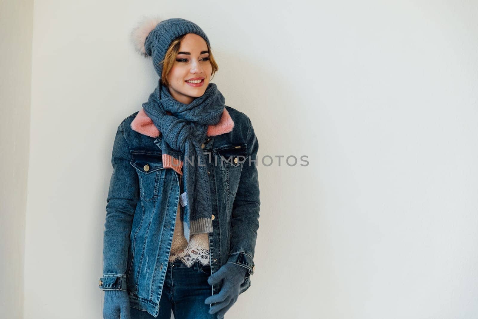 woman with a warm hat with a scarf in winter clothes stands on a white background