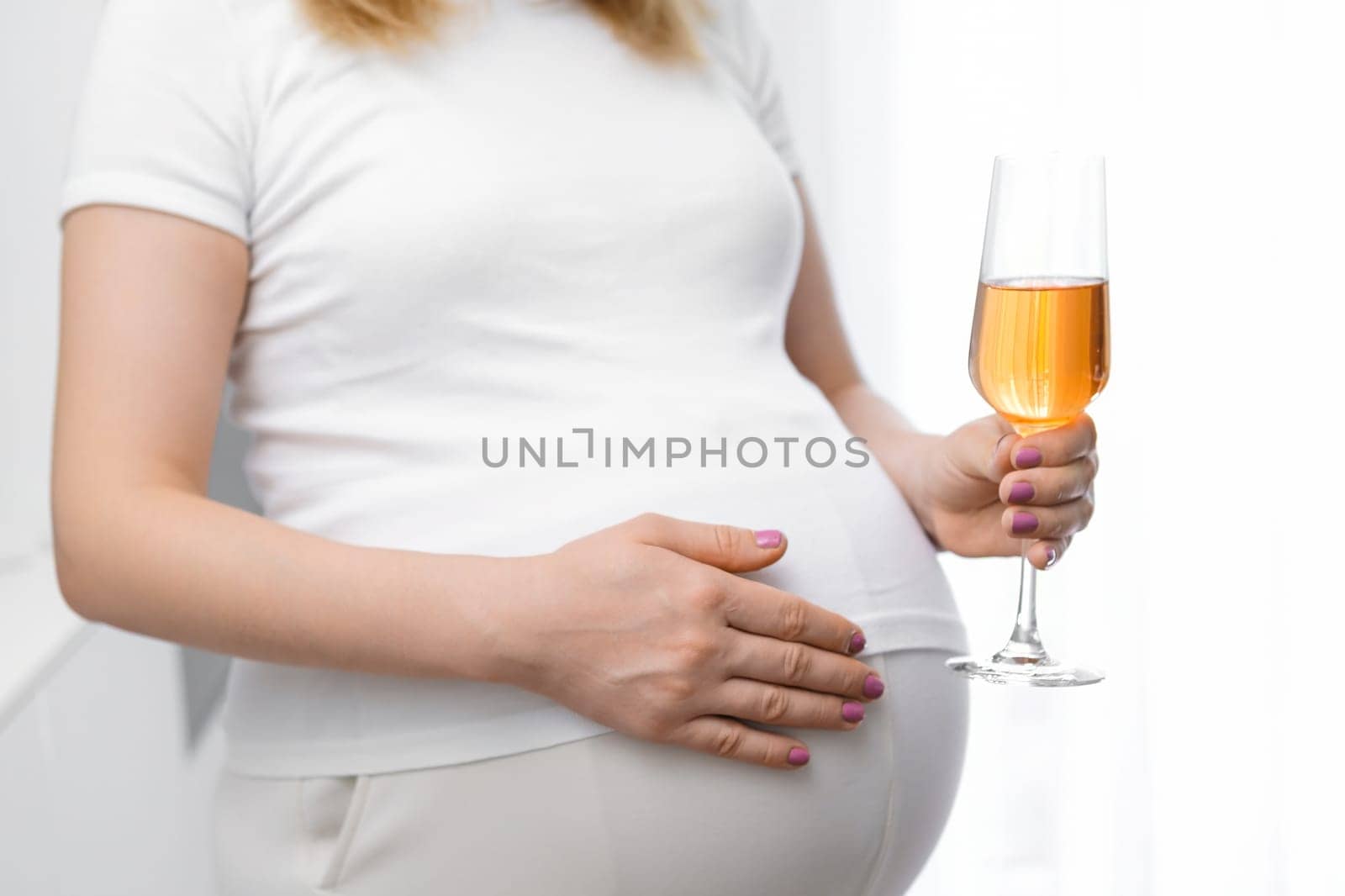 Close up glass of wine in pregnant womans hand. Alcohol during pregnancy
