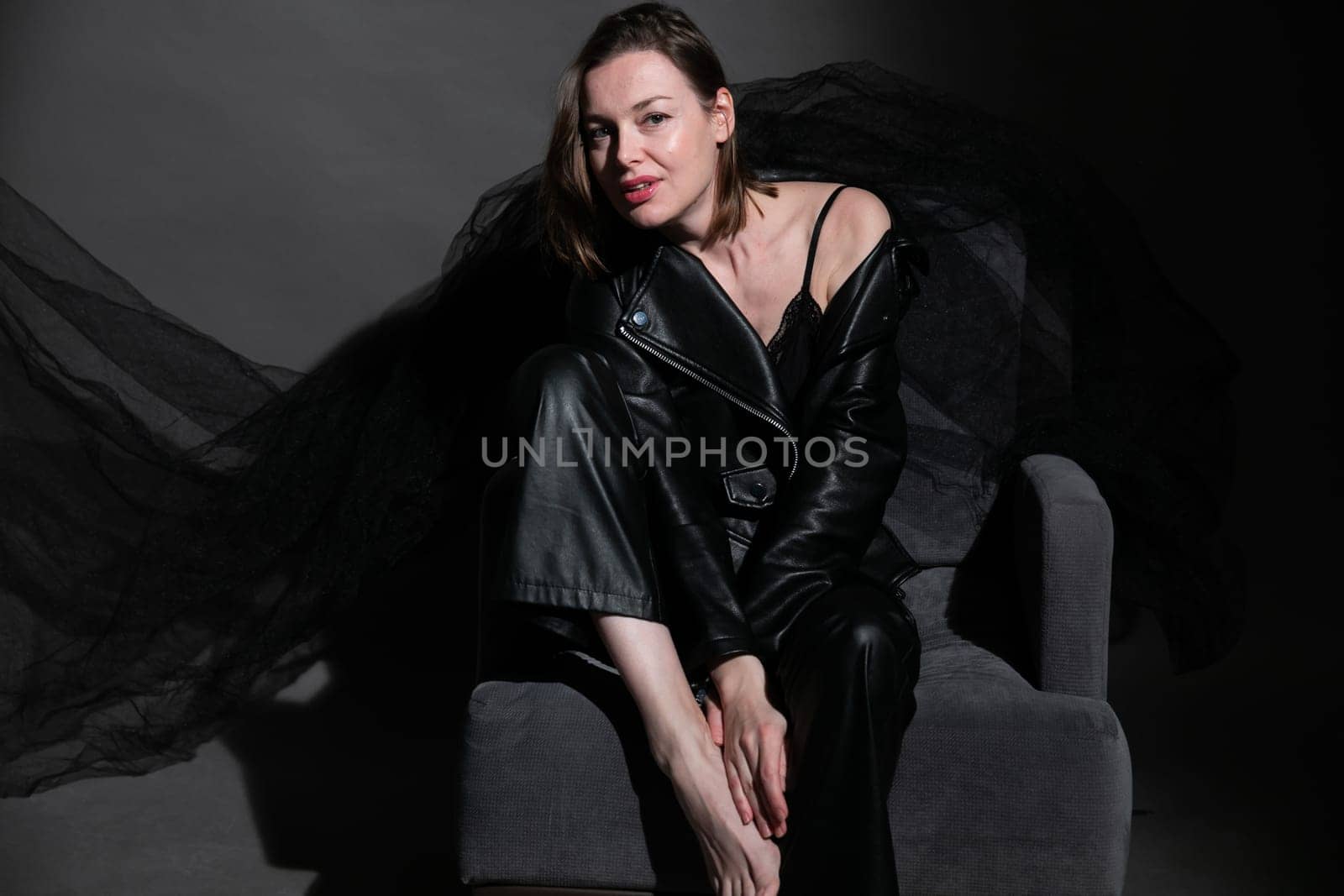 a fashionable woman in black clothes sits on a chair by Simakov