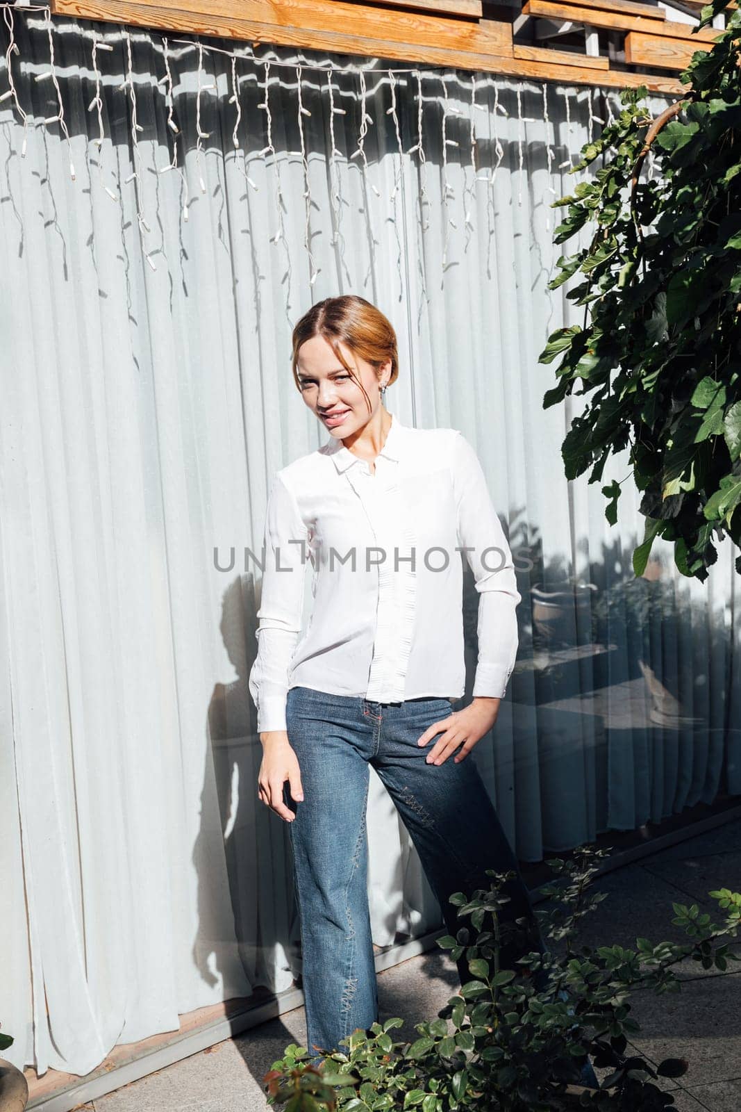 fashionable woman in jeans stands at a window on the street