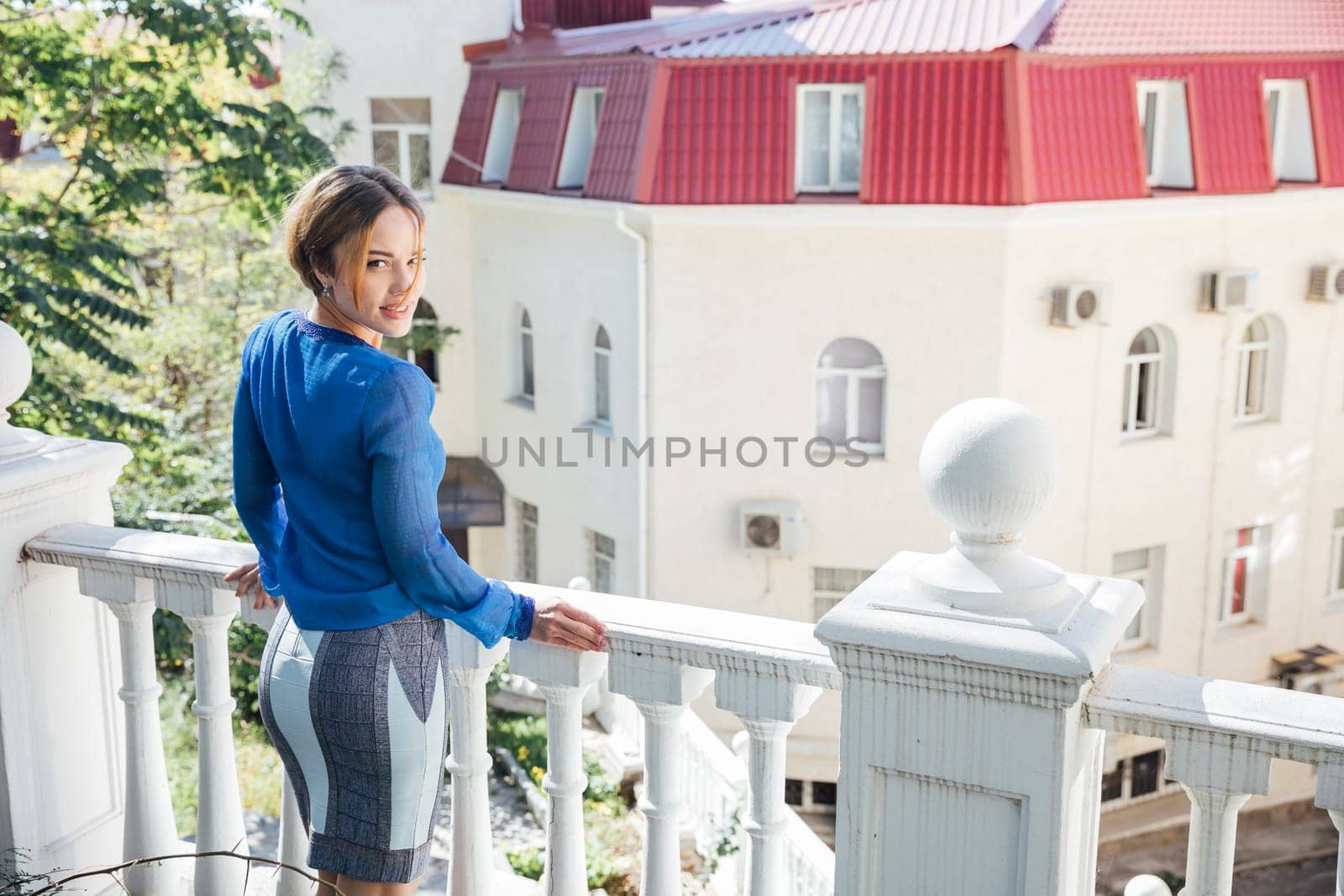 a fashionable woman in blue clothes stands on the street by the railing by Simakov