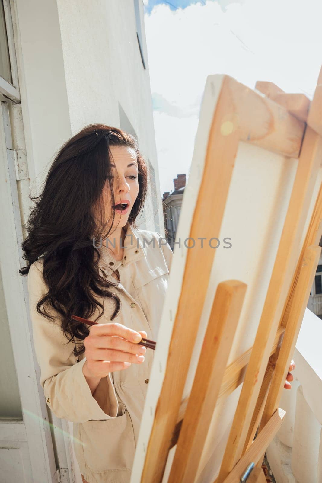 a female artist stands on the balcony by the easel in surprise