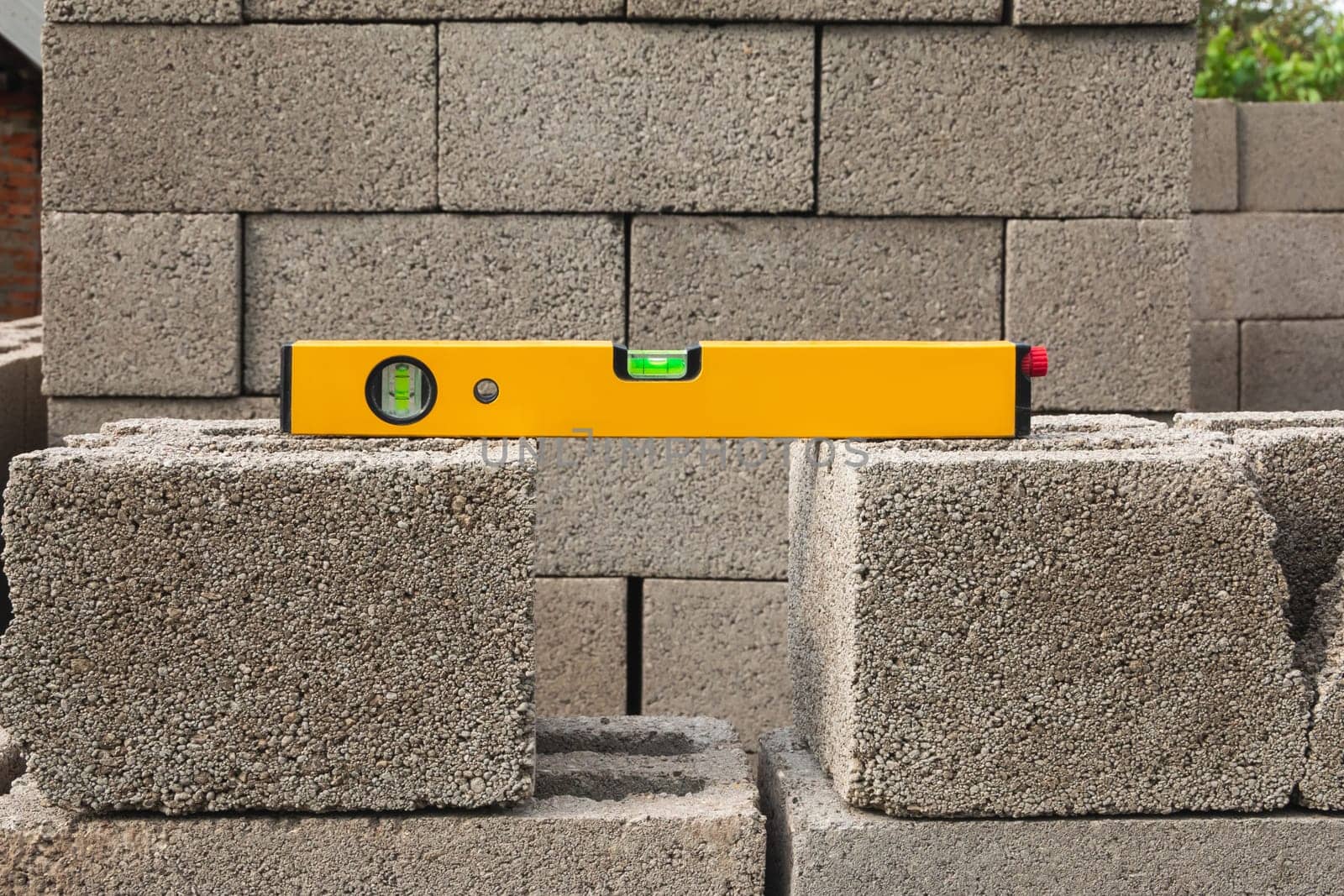 The bubble construction level lies on a cinder block construction stone. It is used by carpenters, masons, installers for various mounting and fastening works