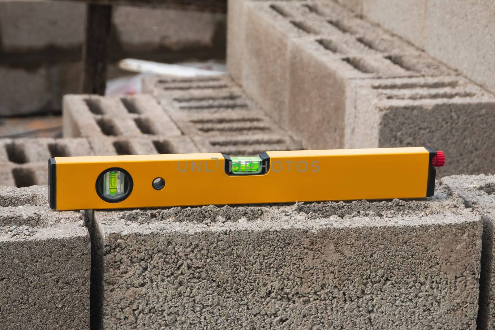 The bubble construction level lies on a cinder block construction stone. It is used to assess the compliance of surfaces with a vertical or horizontal plane, as well as to measure the angular deviatio