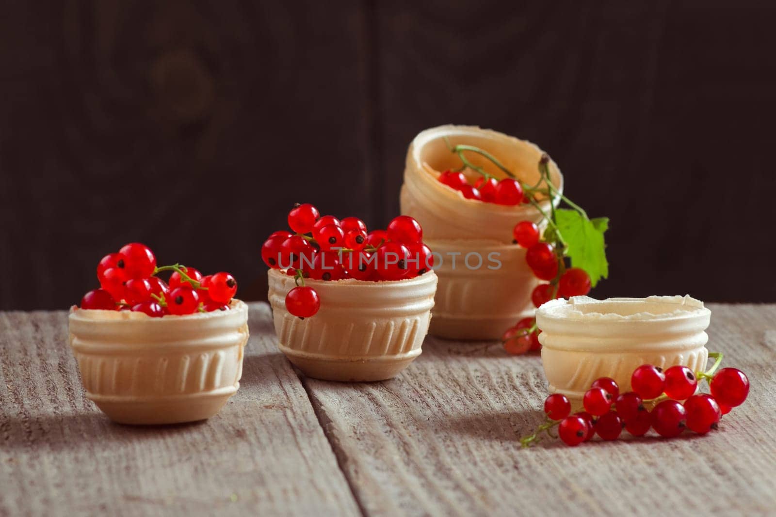 Bunches of red currants in waffle plates on a wooden table. Still life with berries filled with vitamins