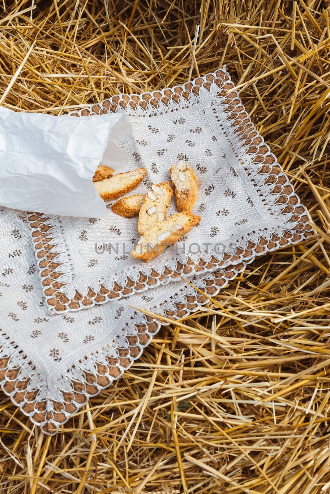 Almond cookies crackers with pieces of nuts lie on a napkin against the background of straw. A snack in nature