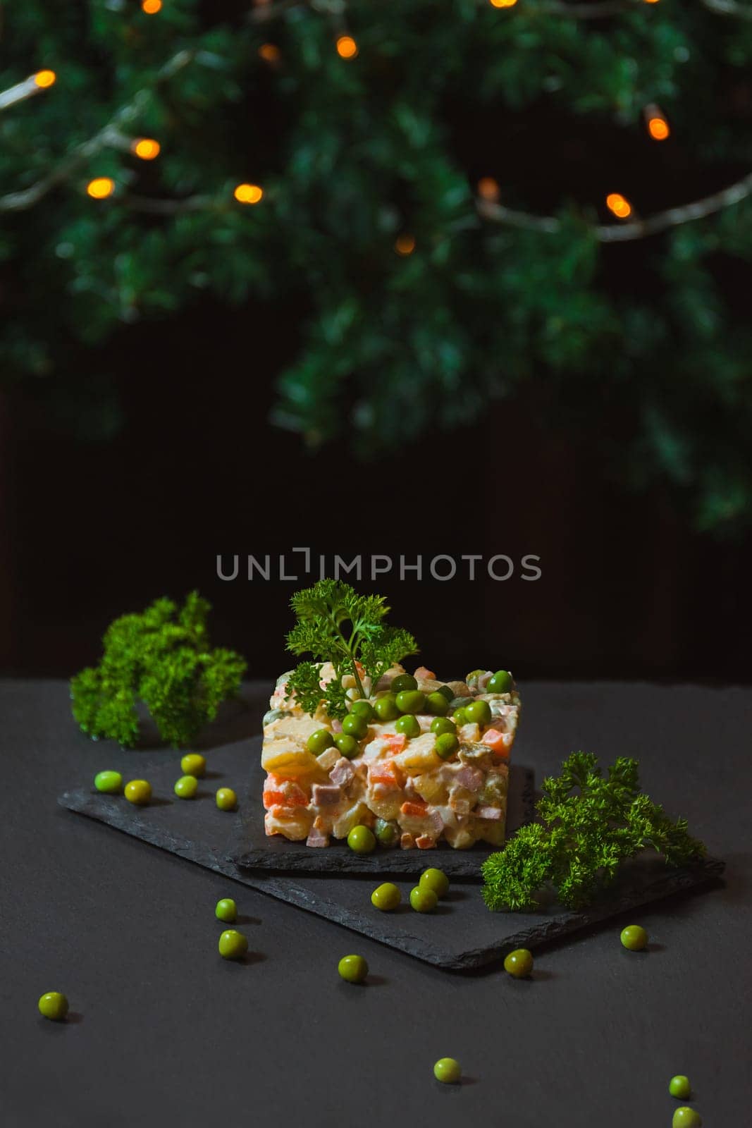 Olivier salad on a dark background in an interesting form of serving and decoration for the New Year and Christmas, with copy space