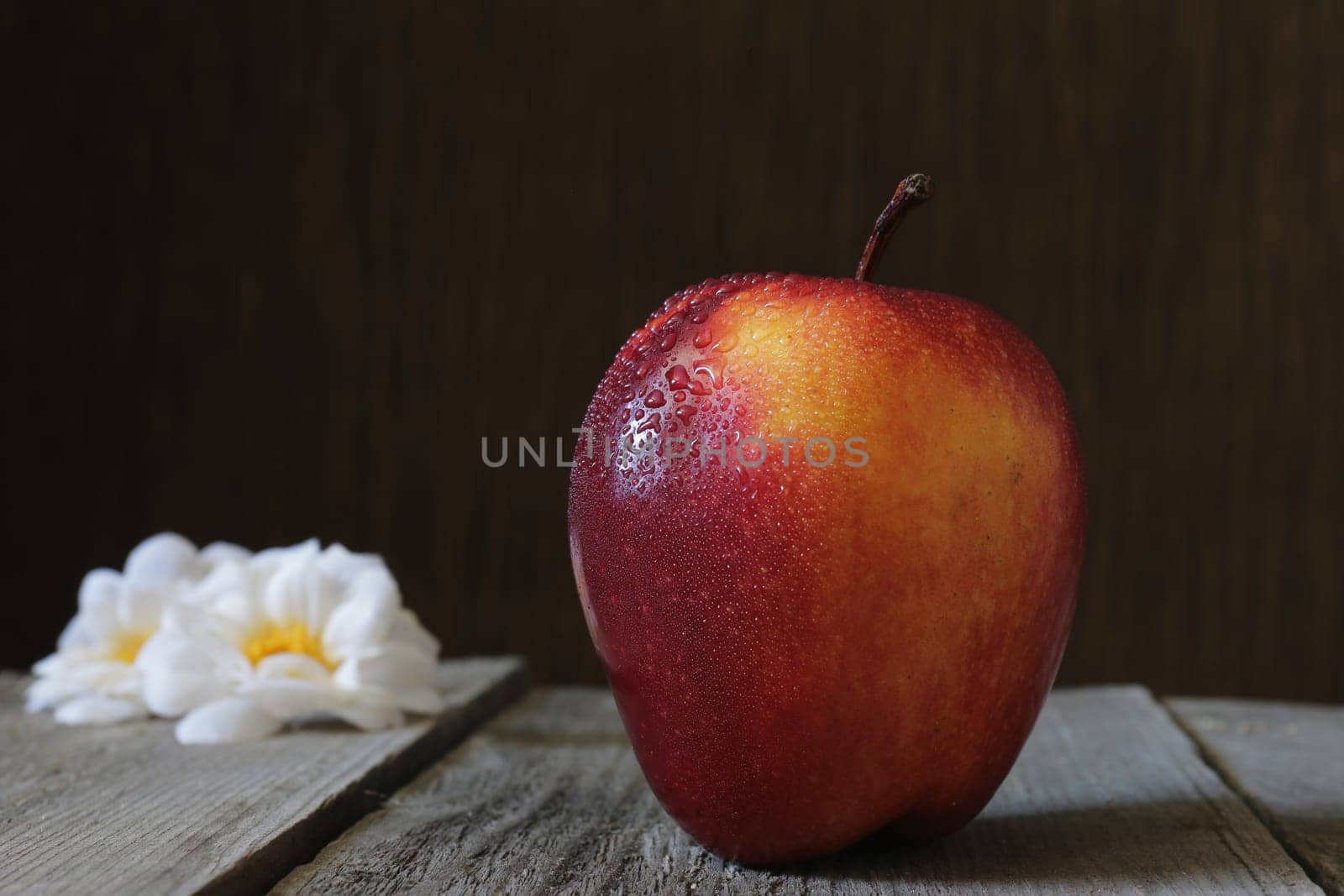 Red apple and flowers on the wooden table