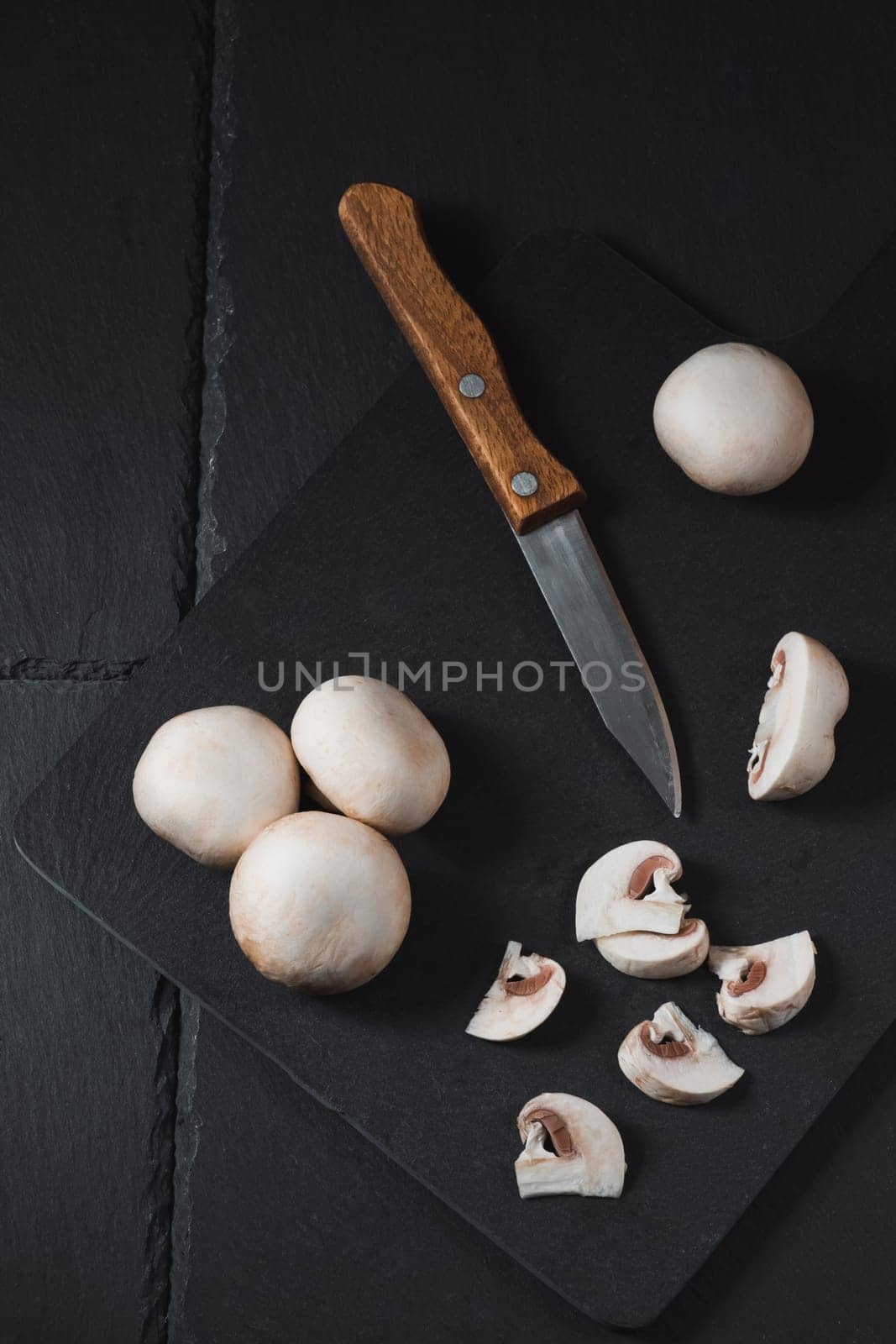 Sliced champignons on a board next to a knife