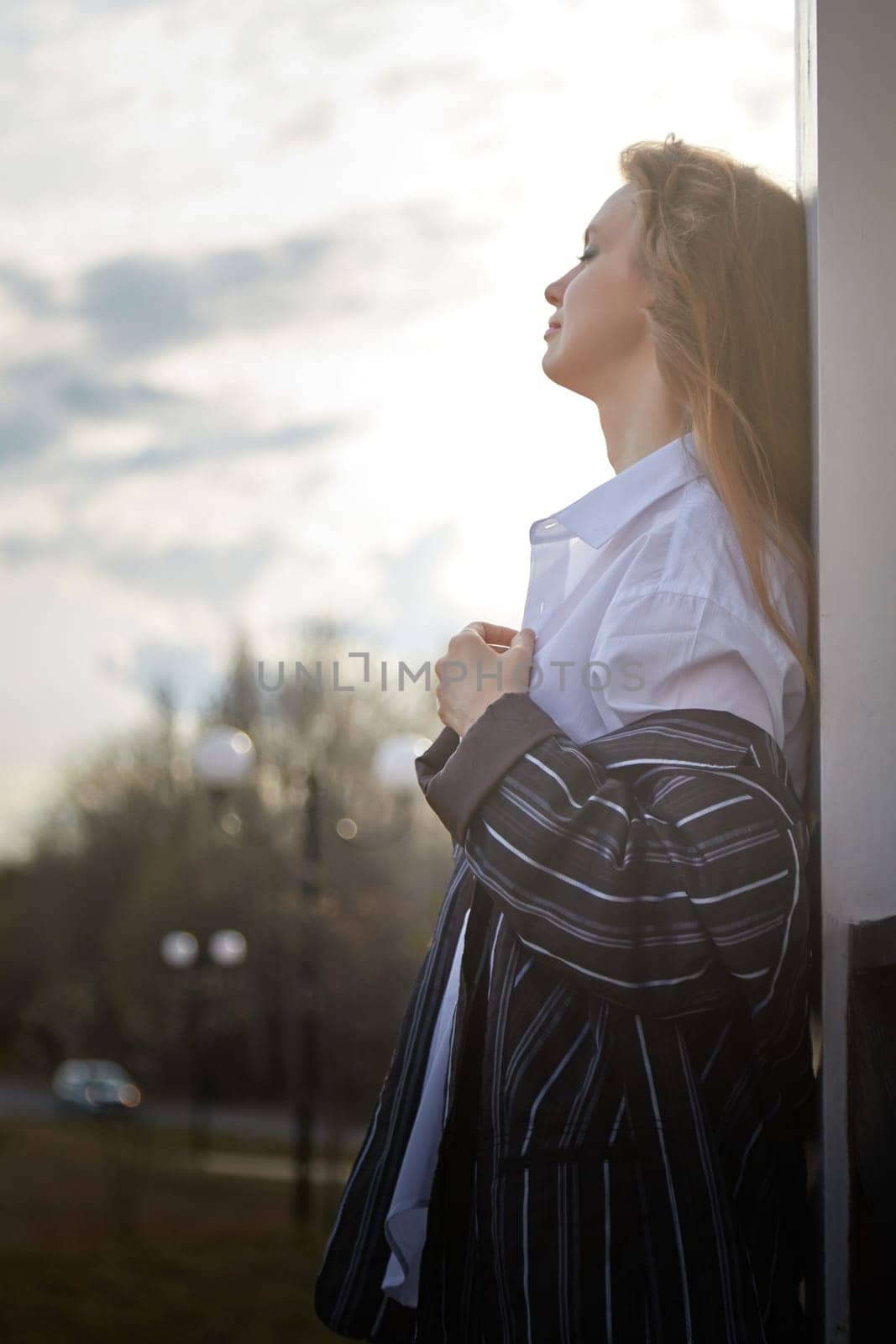 Portrait of Beautiful girl with long blonde hair in white shirt and jacket in village or small town. High young slender woman in an autumn, spring, summer day