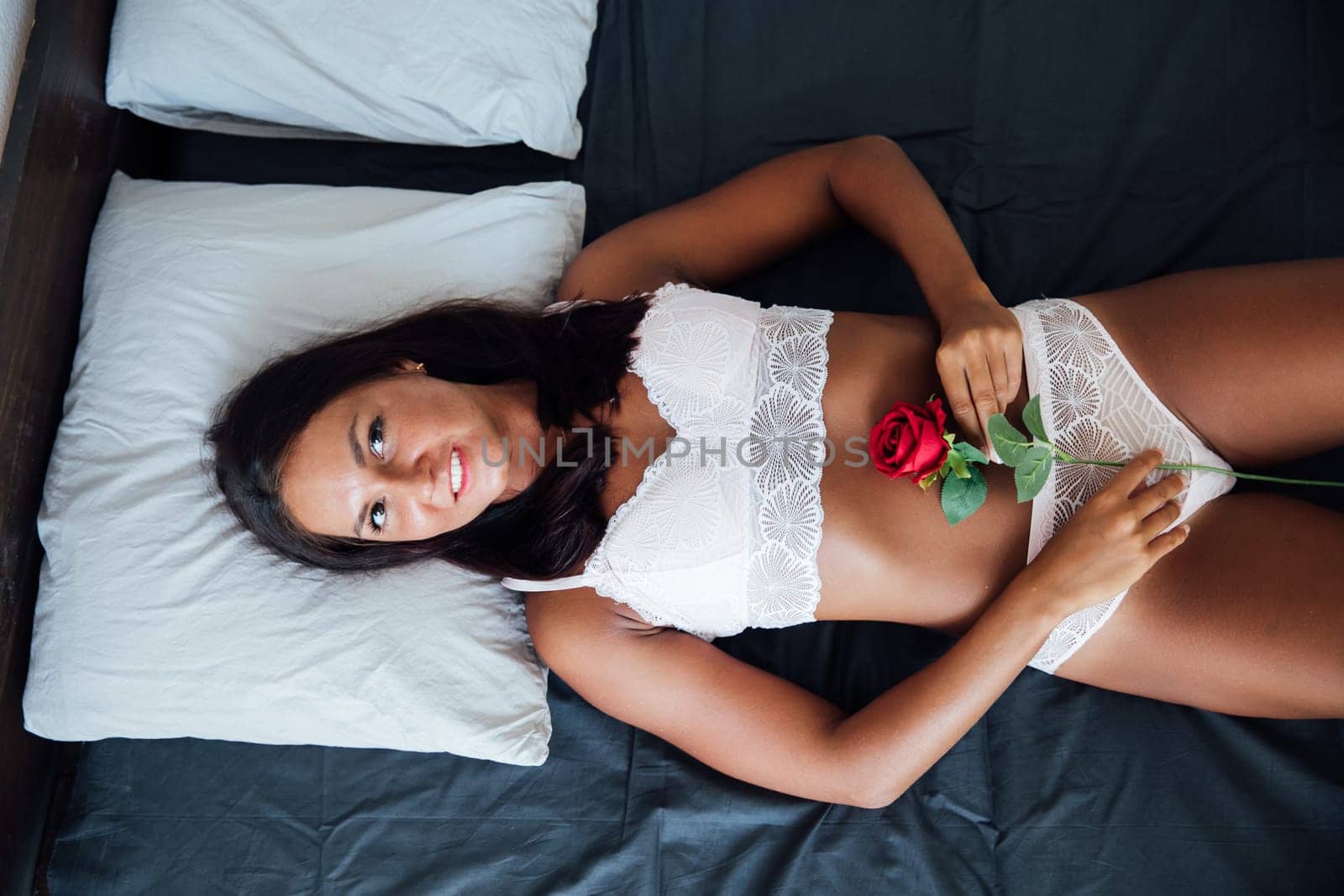 a woman on a bed in a room with a rose flower