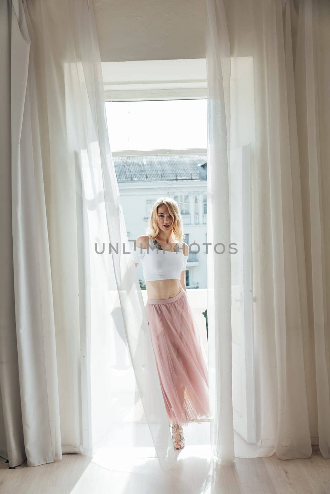 blonde woman stands by the balcony in the room