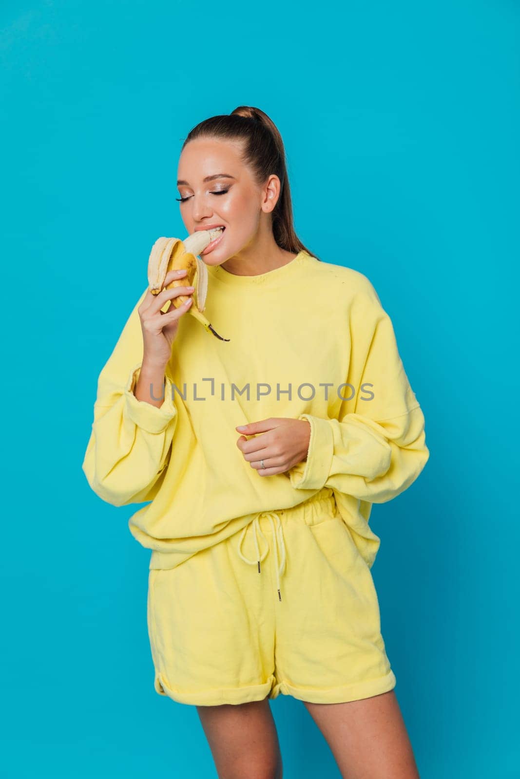 woman in yellow clothes eats a banana