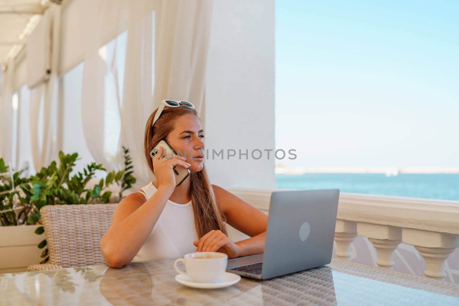 Woman coffee cafe macbook. Woman sitting at a coffee shop with mobile phone drinking coffee and looking away. Caucasian female relaxing at a cafe.