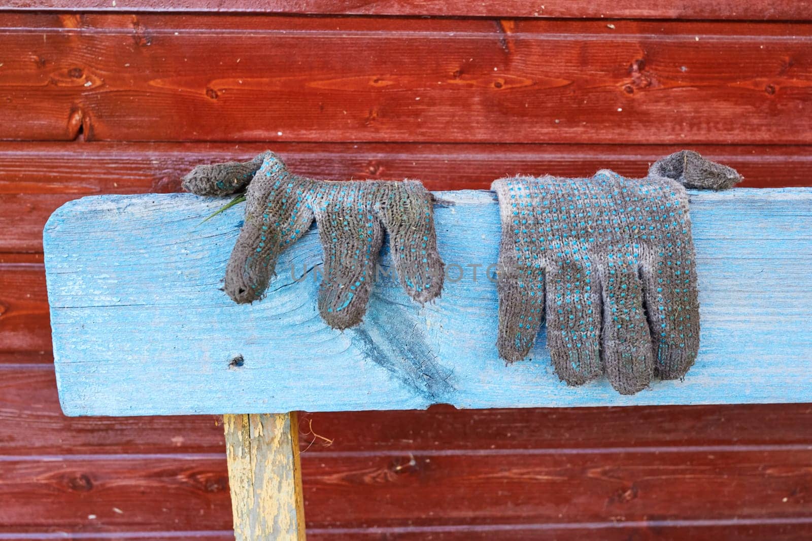 Photo dirty old gardening gloves lie on a blue wooden bench. Gardening. Agriculture. Plant care.